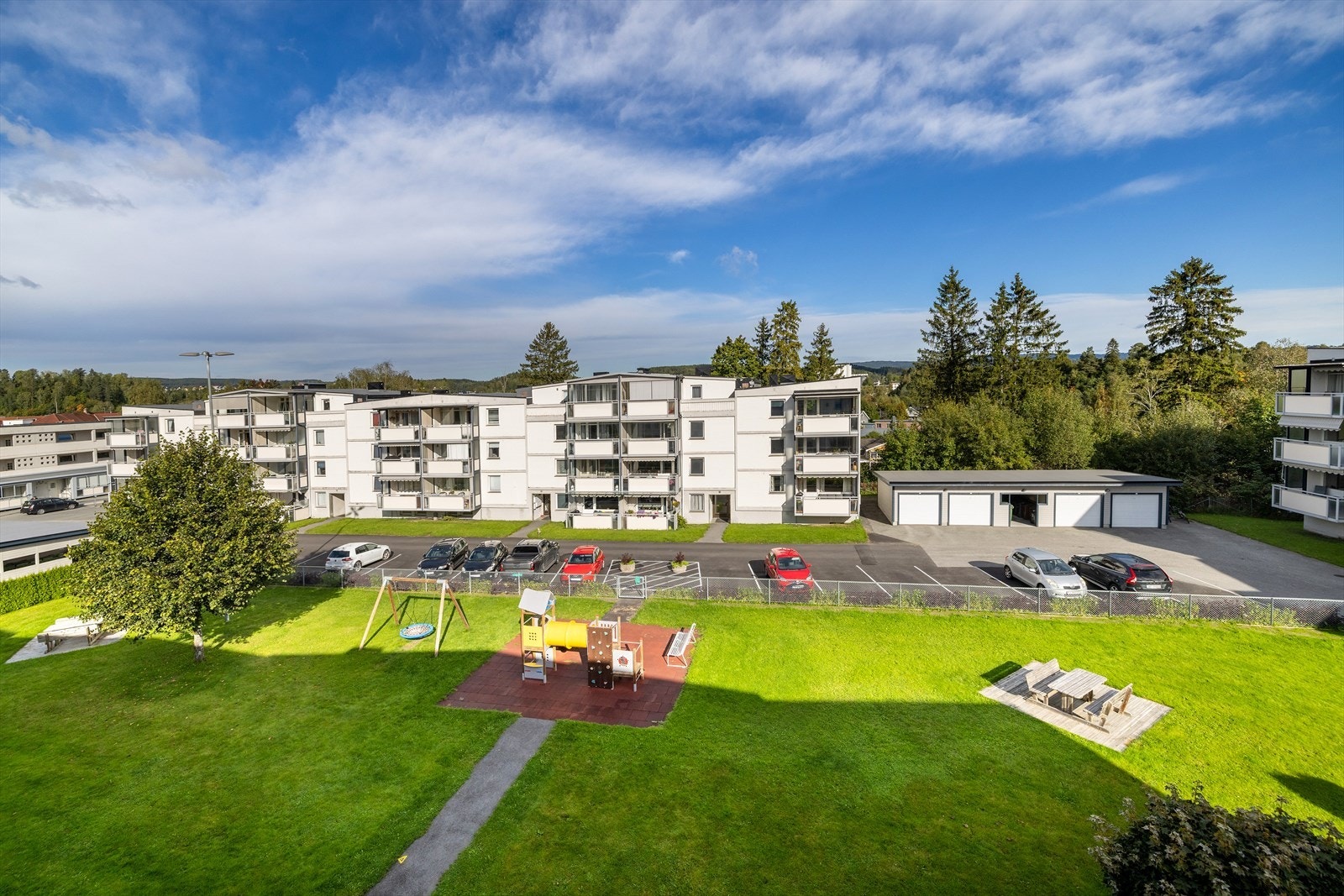 Her er store grøntområder, asfaltert parkering, garasjer, el-bil ladere Galleribilde
