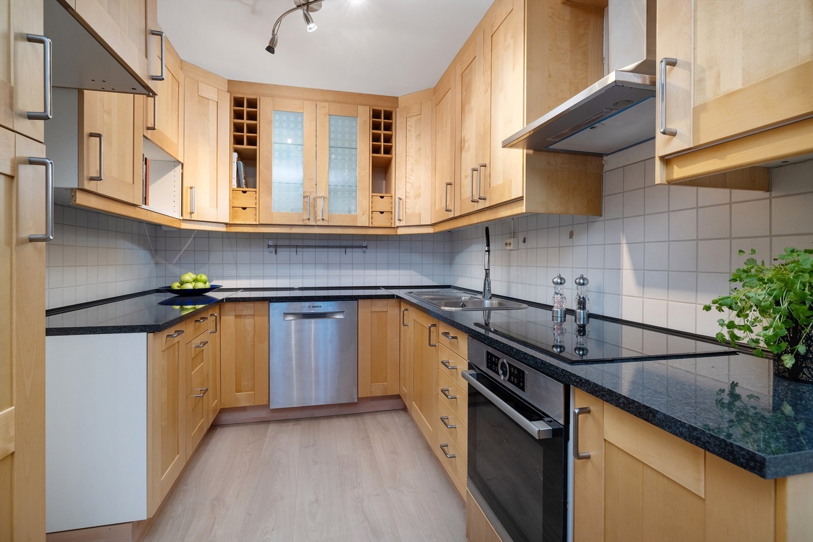 Innholdsrikt kjøkken med oppvaskmaskin og stekeovn med platetopp Galleribilde