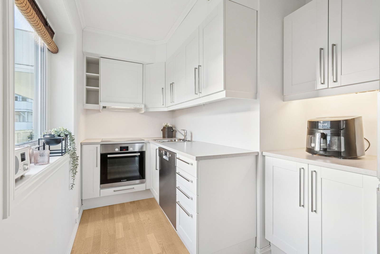 Delikat kjøkken med lyse, profilerte fronter og laminat benkeplate Galleribilde