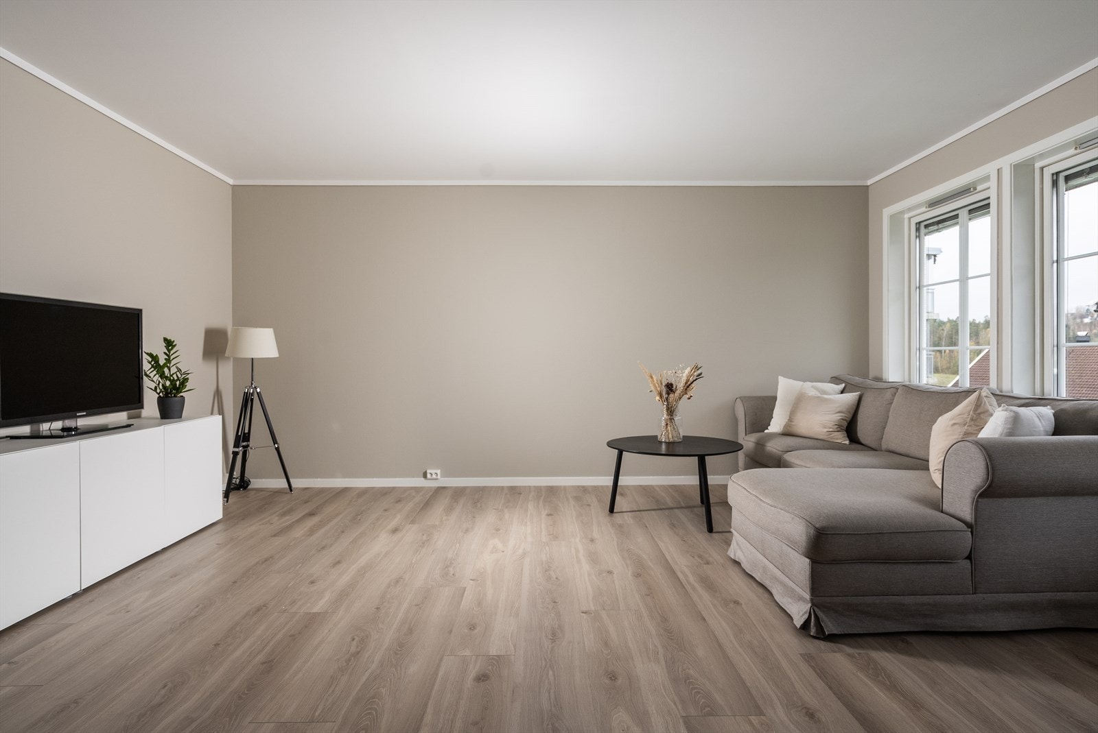 Stuen er lys og innbydende med 1-stavs laminat på gulv og slette vegger malt i en moderne og stilren fargetone. Galleribilde