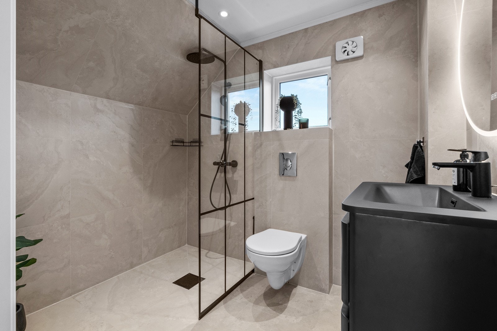 Badet har en vegghengt servantinnredning med skuffer og nedfelt servant, samt dusjhjørne og vegghengt toalett. Galleribilde