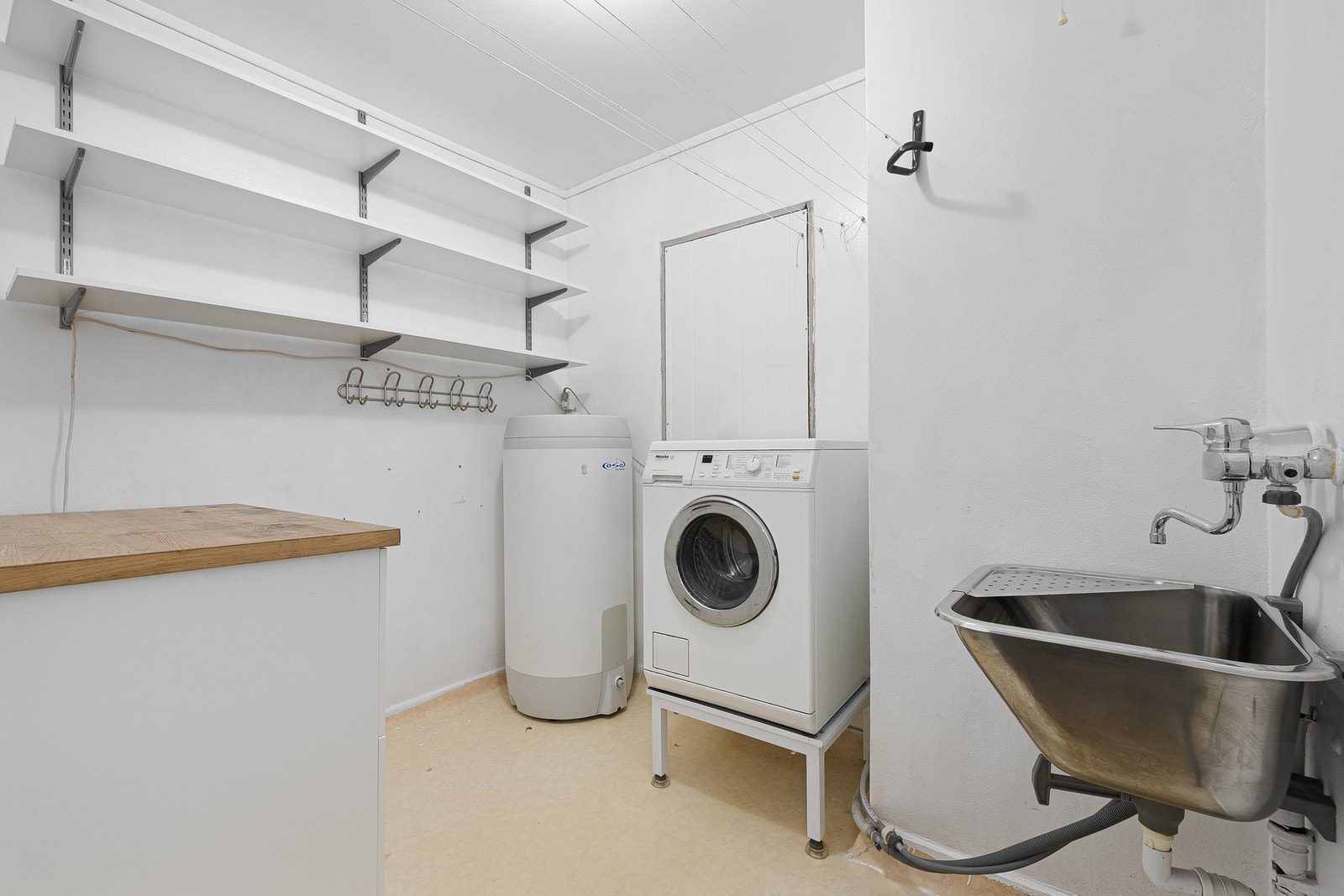 Leiligheten har et praktisk vaskerom med opplegg for vaskemaskin og utslagsvask. Stor varmtvannsbereder fra 2017. Galleribilde