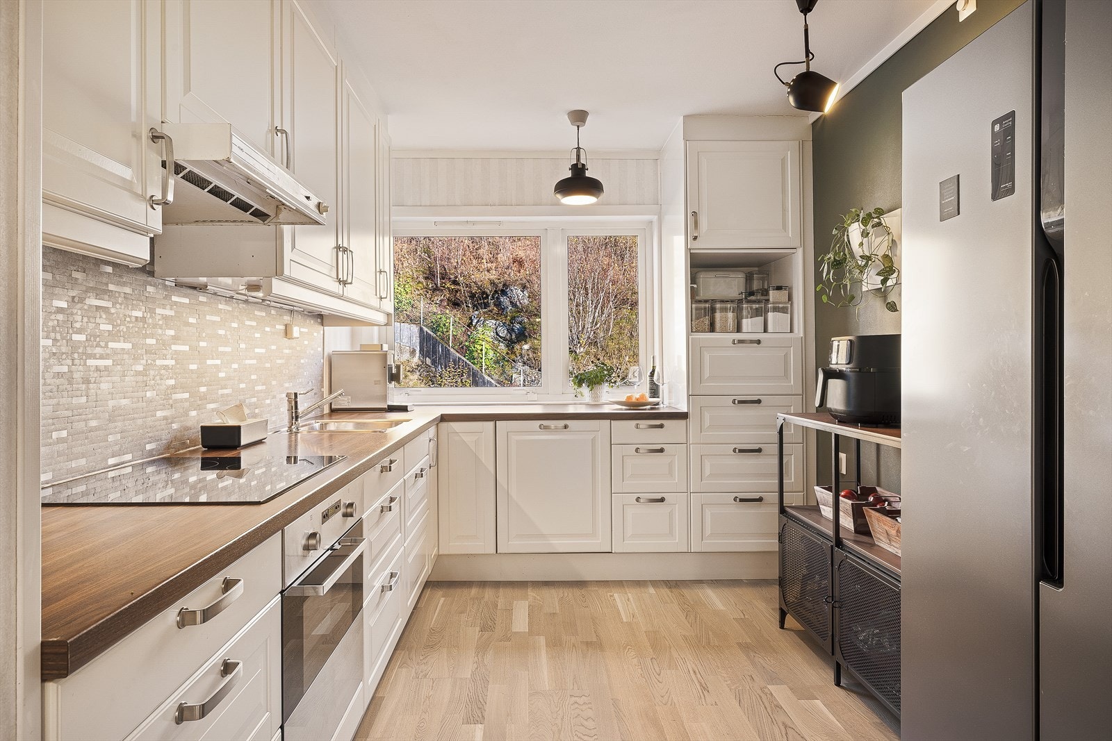 Pent kjøkken med lyse profilerte fronter og rikelig med benk- og skapplass Galleribilde