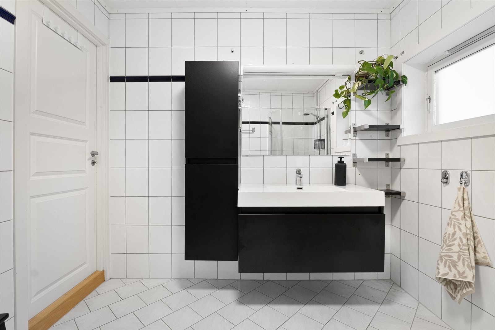 Badet er innredet med toalett, dusjdører og servant med møblement. Galleribilde