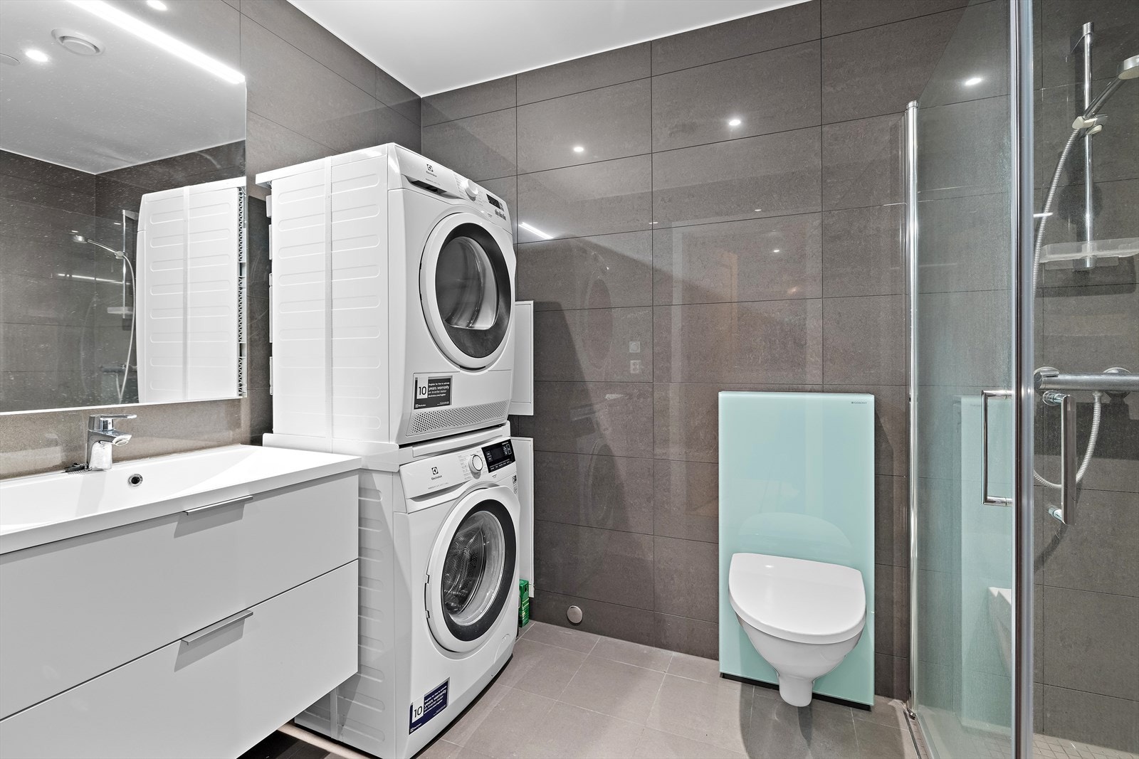 Delikat flislagt bad med vegghengt toalett og dusjnisje Galleribilde