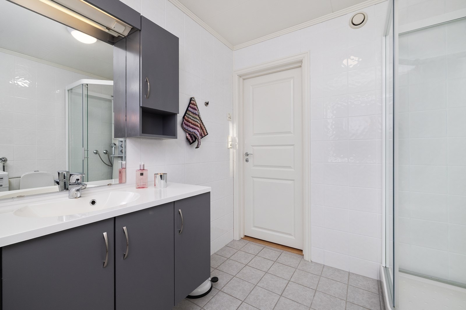 Boligens hovedbad er helfliset og utstyrt med servantinnredning og dusjkabinett. Galleribilde