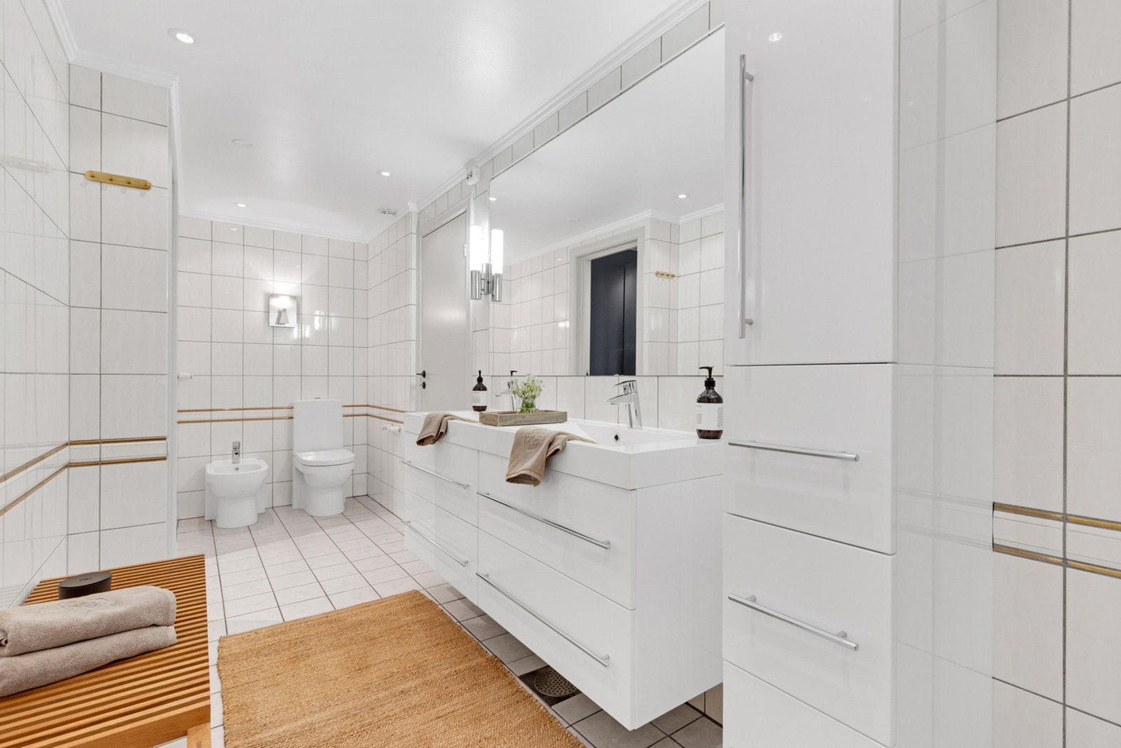 Baderommet er innredet med dobbel servant med underskap og sideskap, dusjkabinett og toalett. Galleribilde