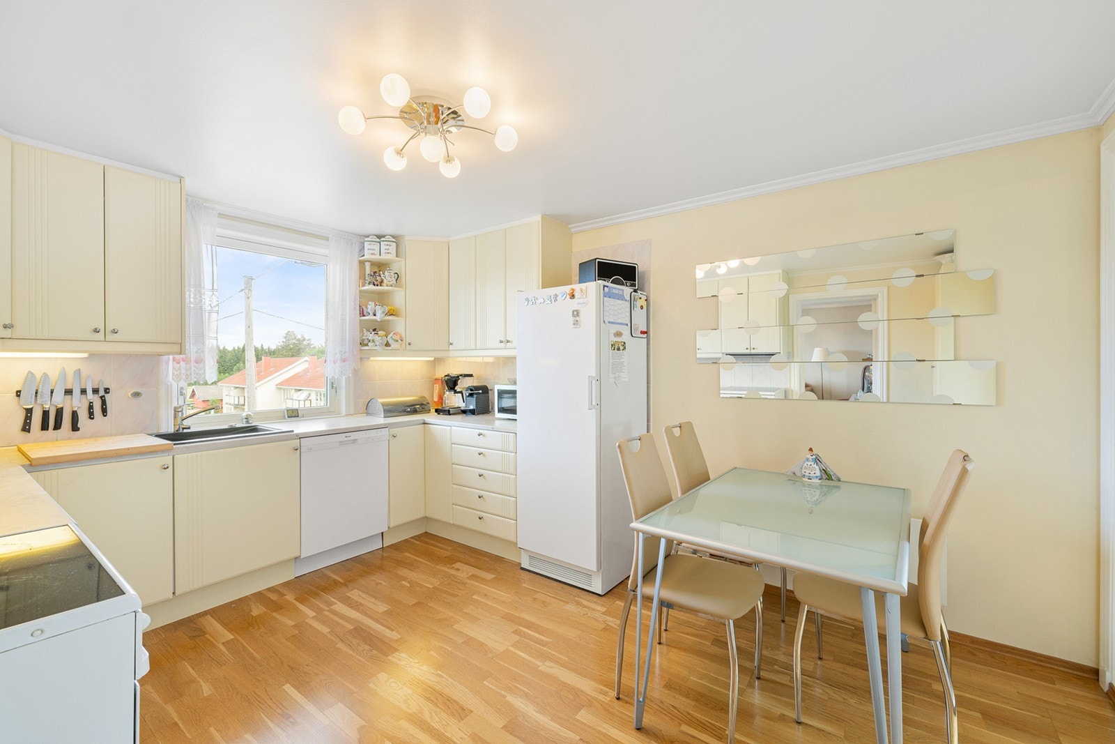 Innredningen består av profilerte skapfronter i lys kremfarge, benkeplate i laminat og fliser mellom benk og overskap. Kjøkkenet er utstyrt med frittstående hvitevarer som inkluderer komfyr, kjøleskap med frysedel og en oppvaskmaskin. Galleribilde