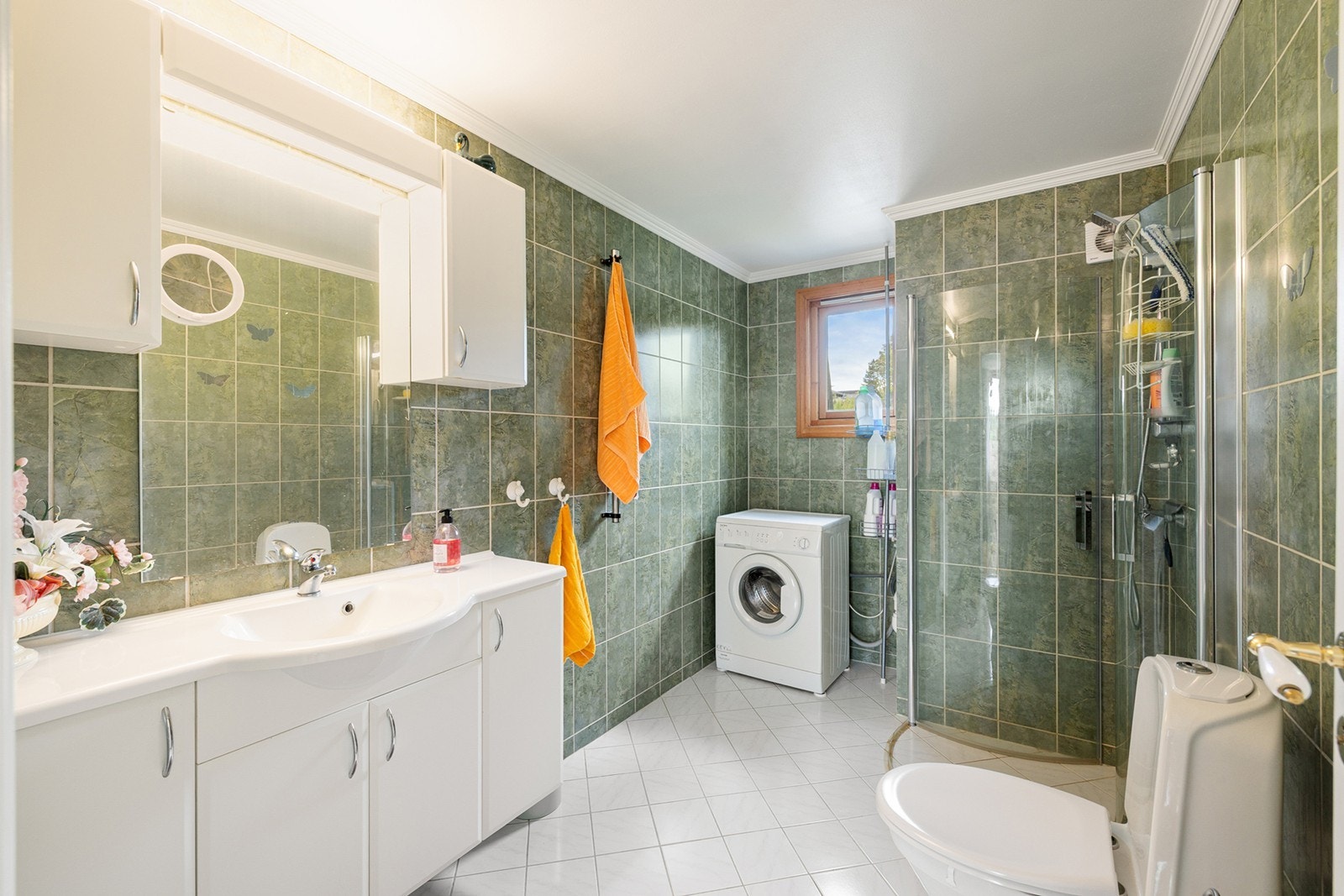 Badet i 3. etasje har flislagte gulv og vegger. Rommet er innredet med hvit baderomsinnredning med profilerte fronter, servant i helstøpt plate med integrert vask, kromfarget blandebatteri, to sideskap og speil med belysning. Galleribilde