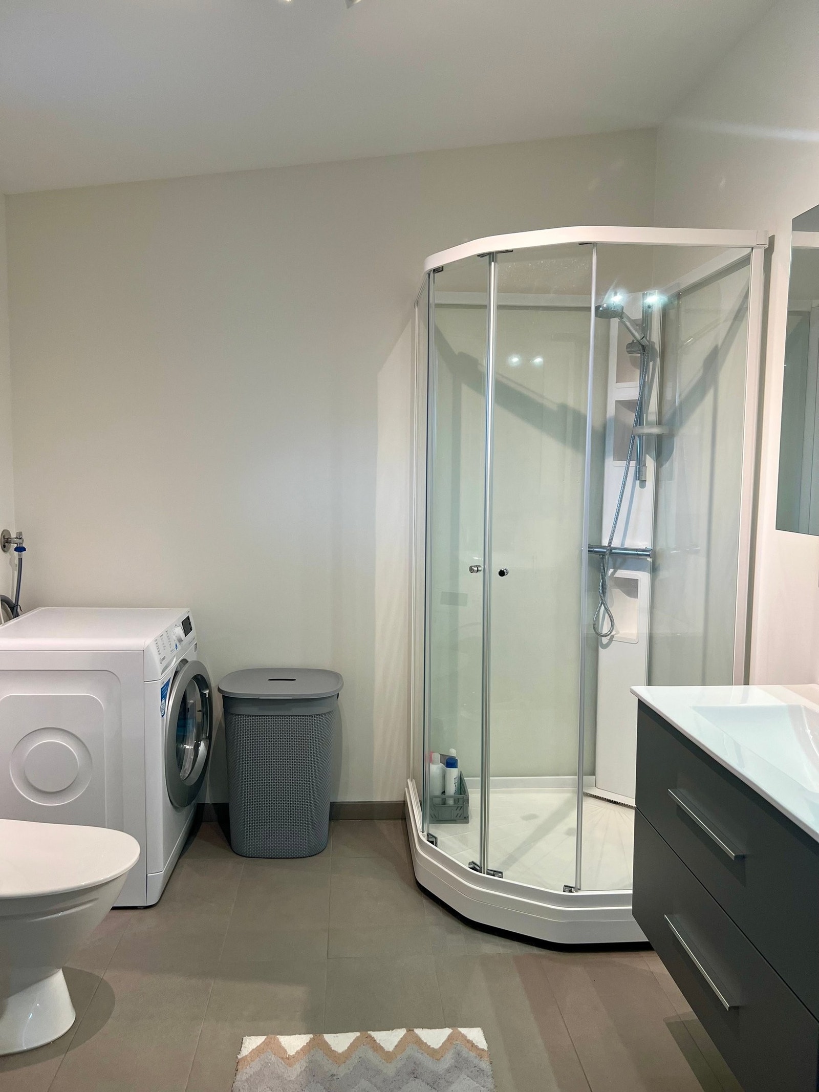 Romslig bad med dusjkabinett, servant, høyskap og opplegg til vaskemaskin. Galleribilde