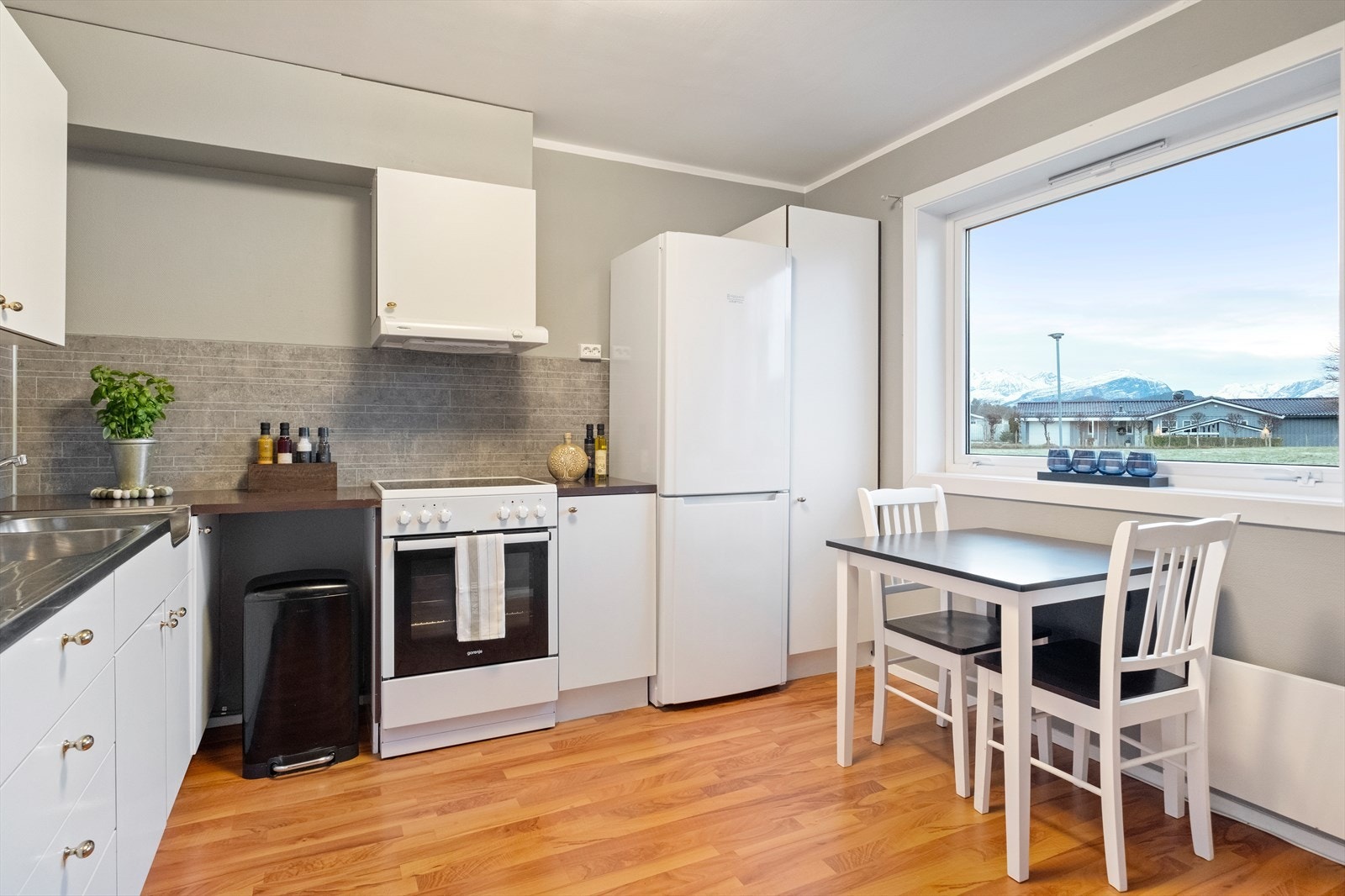 Lyst kjøkken med laminatgulv og praktisk spiseplass ved vinduet. Galleribilde