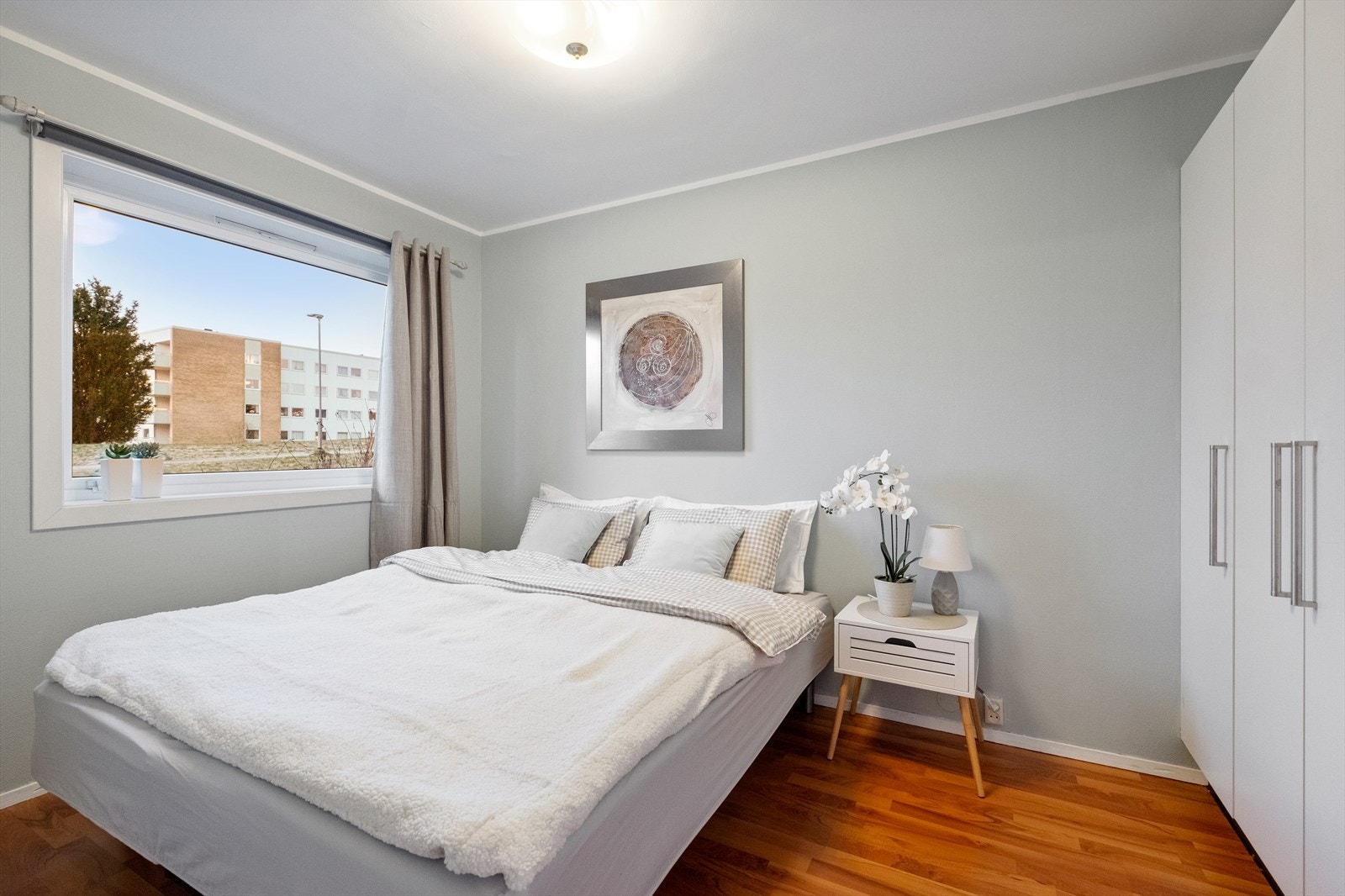 Store vinduer gir godt lysinnslipp til soverommet, som har malte vegger og parkettgulv. Galleribilde