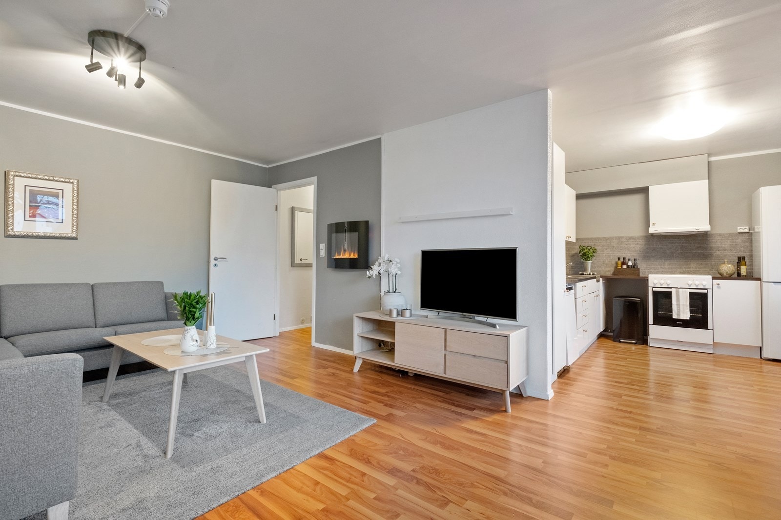 Laminatgulv strekker seg gjennom stue og kjøkken, og gir en helhetlig følelse. Galleribilde