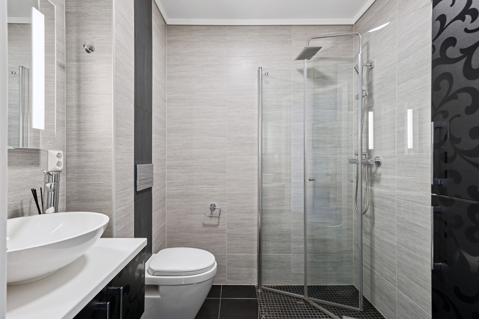 Boiligen har to flotte bad. Ett i hver etasje. I 1.etasje finner man et flott, helfliset bad utstyrt med vegghengt toalett, dusjhjørne, servant med underskap, vegghengt speil med lys og høyskap fra Foss Bad. Galleribilde