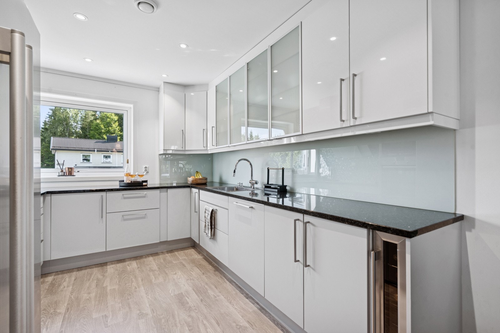 Den frostede glassplaten bak vasken er både funksjonell og bidrar til et elegant og sofistikert inntrykk i rommet. Oppvaskmaskinen er stor og helintegrert, med ekstra bestikkskuff øverst som gir god plass til bestikk og kjøkkenredskaper. Galleribilde