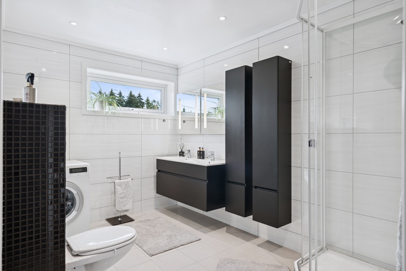 Det flotte og store helfliset badet er utstyrt med vegghengt toalett, dusjkabinett fra Porsgrund Bad, to servanter med underskuffer med god oppbevaringsplass. Galleribilde