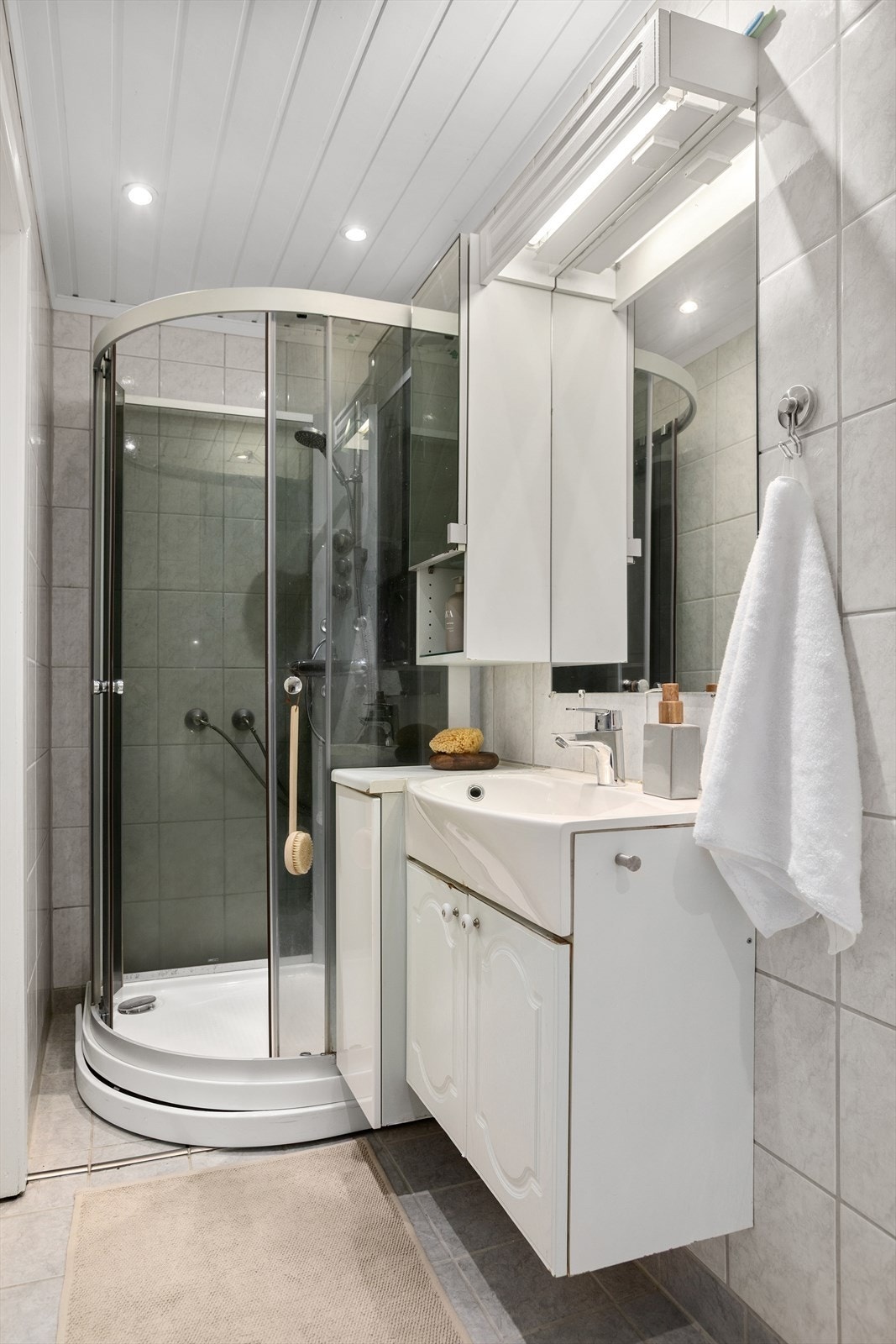 Flislagt bad med dusjkabinett og vegghengt innredning Galleribilde