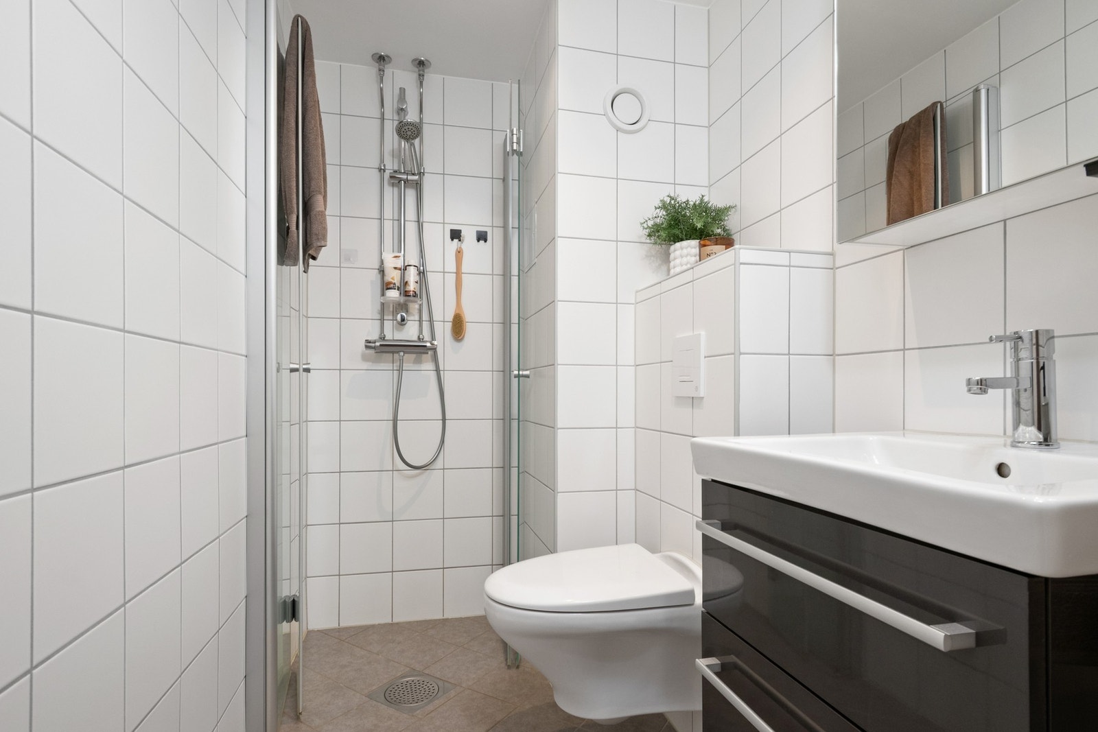 Badet ble pusset opp i 2019, innredet med hvite veggfliser og lysegrå gulvfliser for et delikat uttrykk. Galleribilde