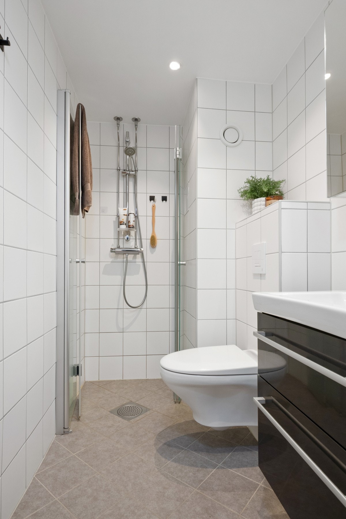 Varme er lagt i gulvet, og badet har downlights, vegghengt toalett og et dusjhjørne med innfellbare glassdører. Galleribilde