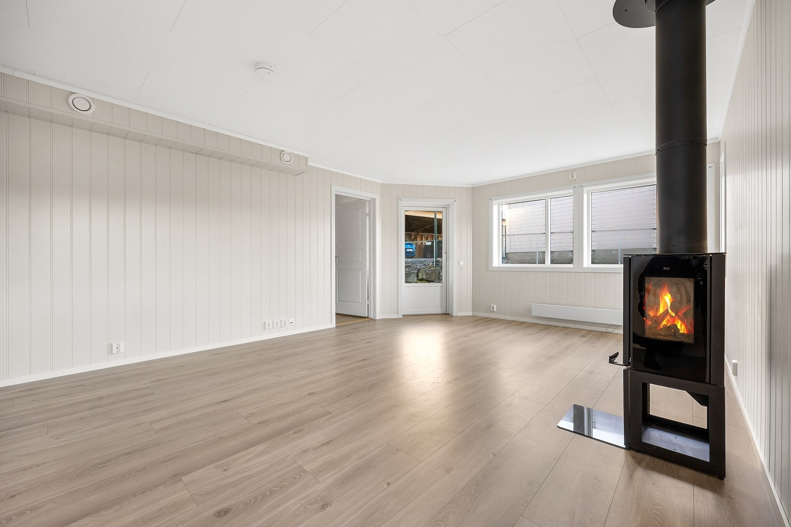 En stilren vedovn tilkoblet isolert stålpipe gir effektiv og stemningsfull varme. Galleribilde