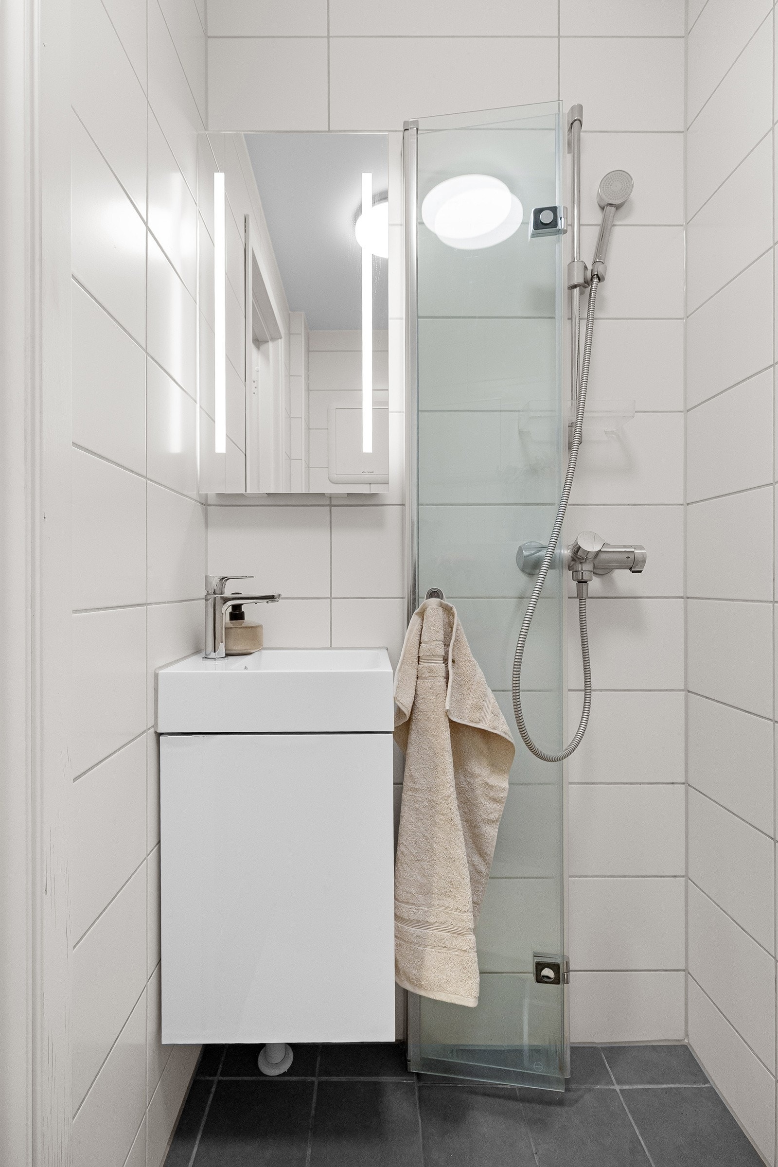 Badet ble oppgradert i 2022, som inkluderer membran, sluk, overflater og sanitært utstyr. Rommet har grå 20x20cm fliser på gulv og hvite 20x50cm fliser på vegger, samt malt himling Galleribilde