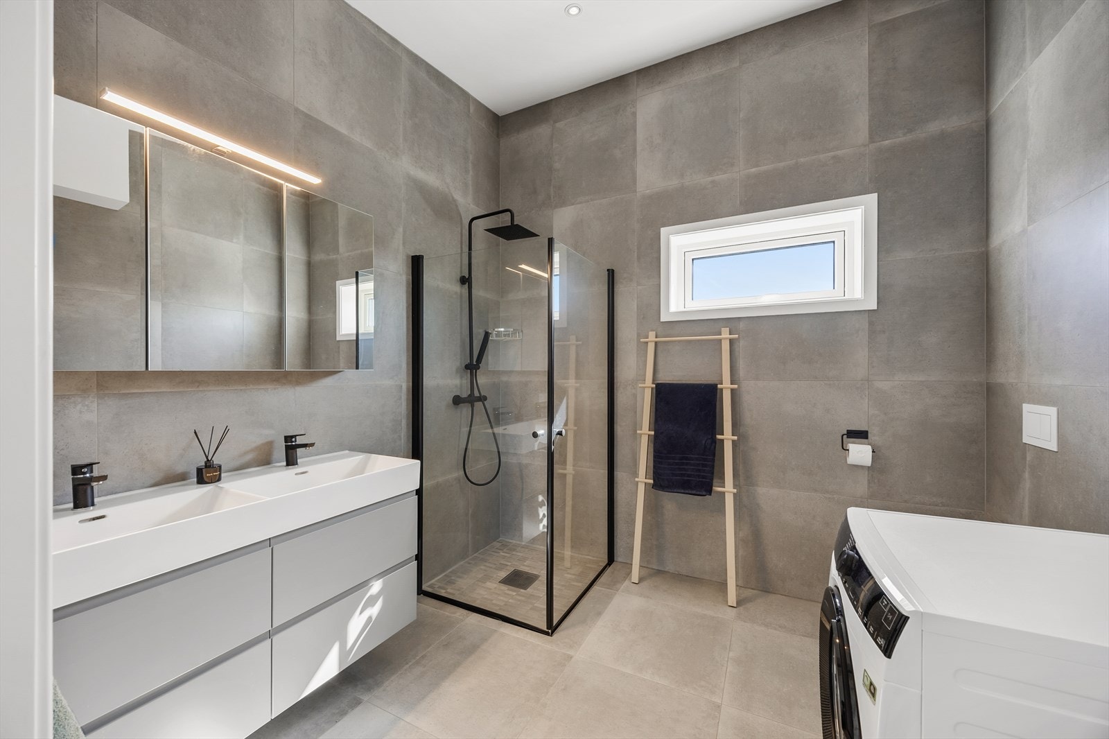 Heldekket bad med doble servanter og dusjhjørne, samt opplegg for vaskemaskin. Galleribilde