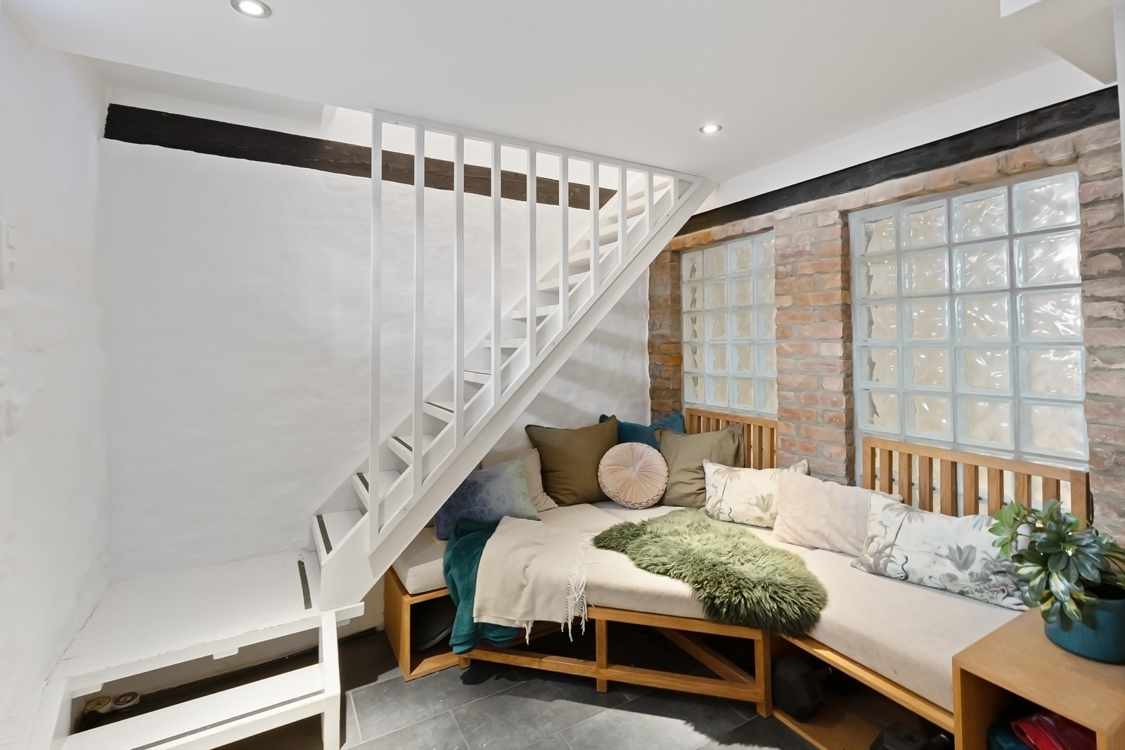 Fra trappen ned til kjelleren møtes du av en praktisk og innbydende kjellerstue, perfekt for avslapning eller ekstra oppholdsrom. Galleribilde