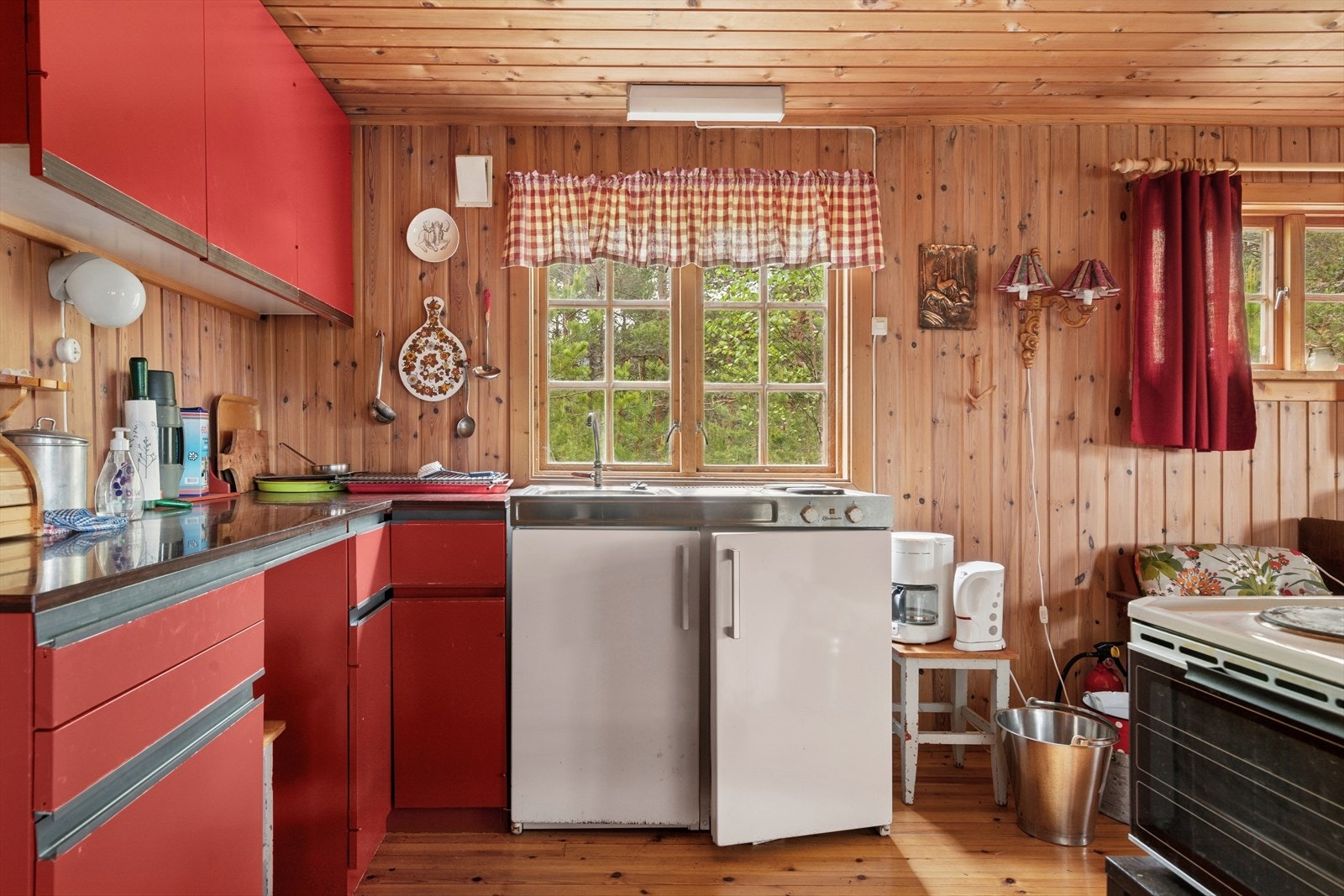 Innredningen er oppført i vinkel og har slette rødmalte overflater på fronter, overskap og underskap samt ett malt hjørneskap. Benkeplaten er laminert foliert. Galleribilde