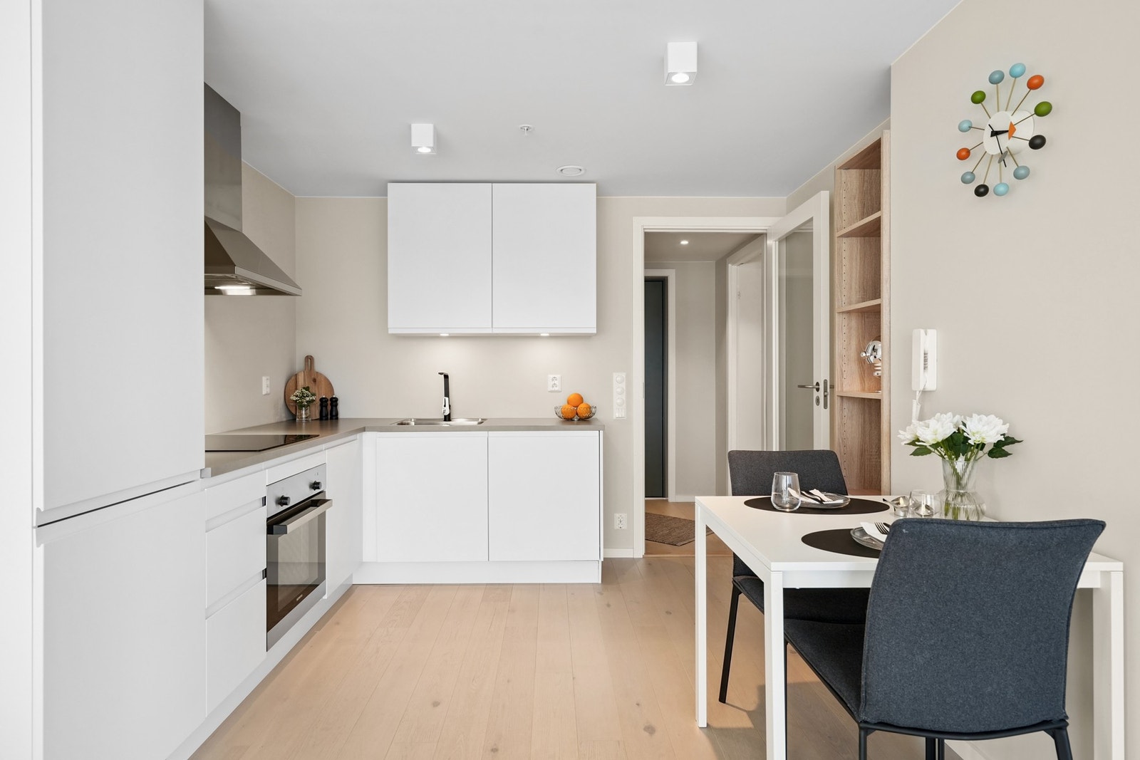 Flott og moderne kjøkken med innredning fra HTH, hvite glatte fronter og flere integrerte hvitevarer. Galleribilde