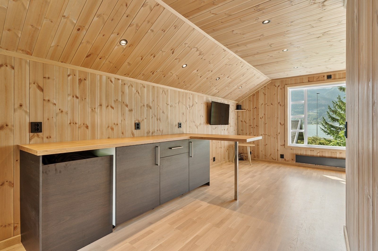 Rommet over garasjen har panelte vegger og spotbelysning i himling - et lyst og brukervennlig areal med mange muligheter. Garasjen er ikke tilkoblet vann eller avløp, kun montert. Galleribilde