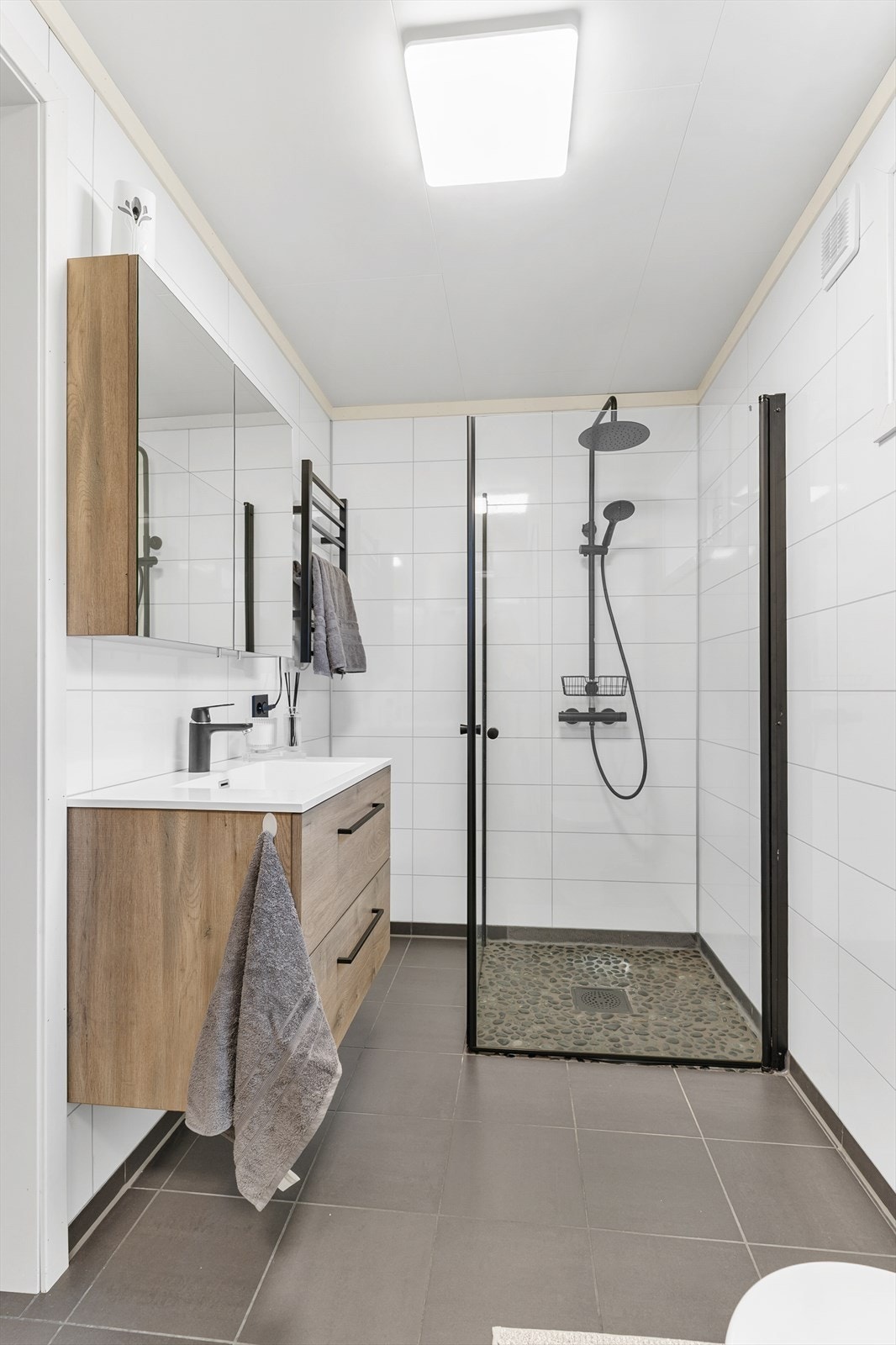 Badet har plater på vegg og flislagt gulv med gulvvarme. Galleribilde