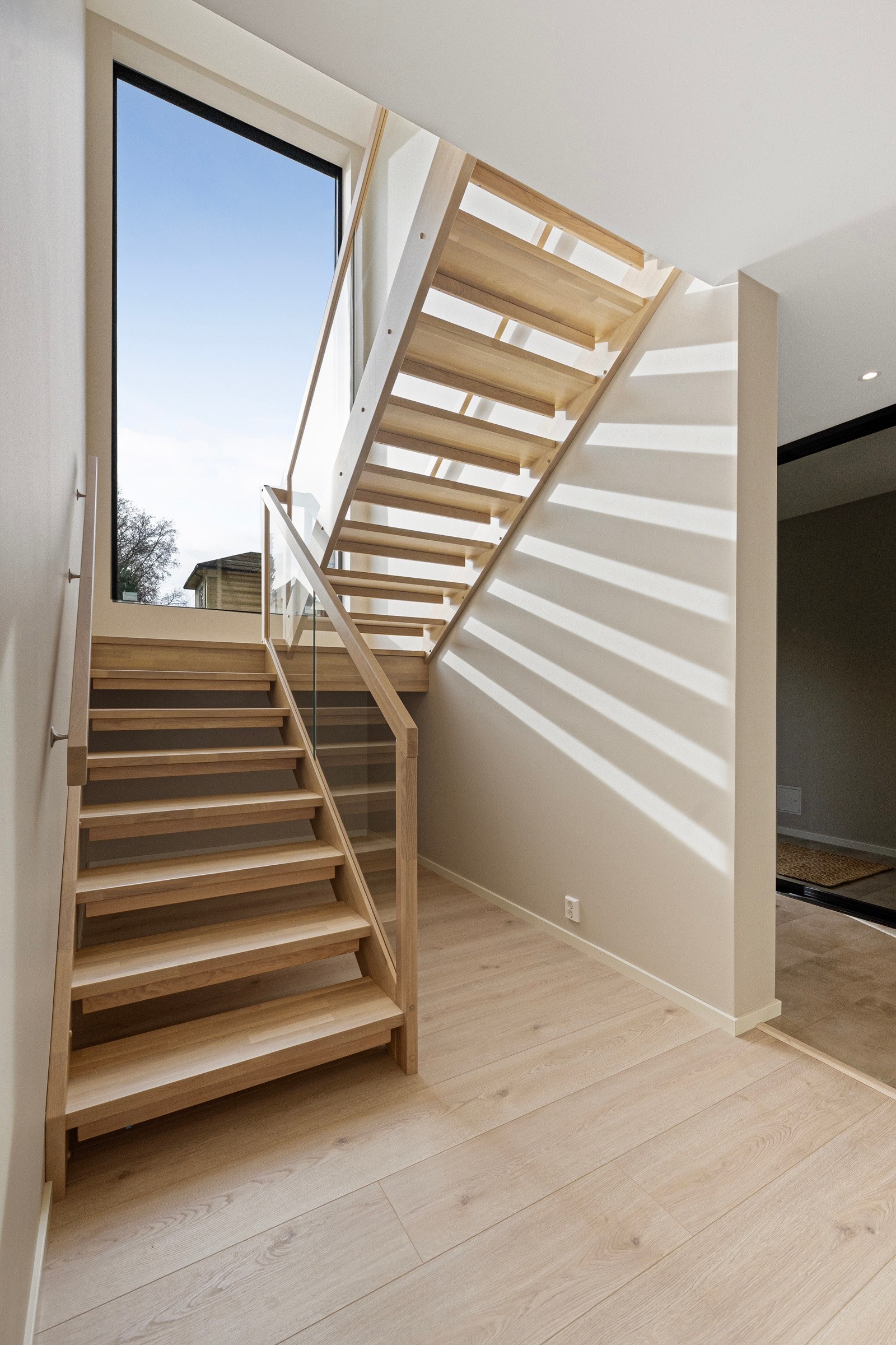 Trapp i treverk mellom etasjene med glass i rekkverk. Galleribilde