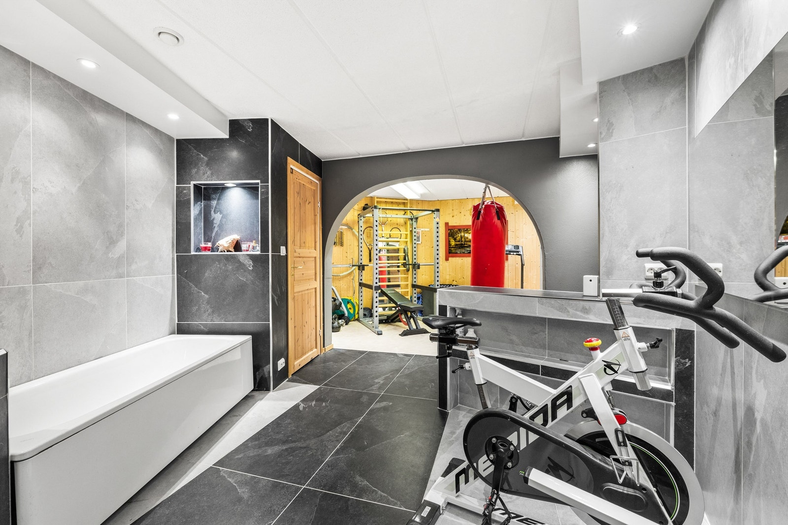 Badet har moderne fliser og fremstår moderne. Det er laget til et treningsrom rett ved siden av, som gjør at man kan ha alt man trenger i eget hus. Galleribilde