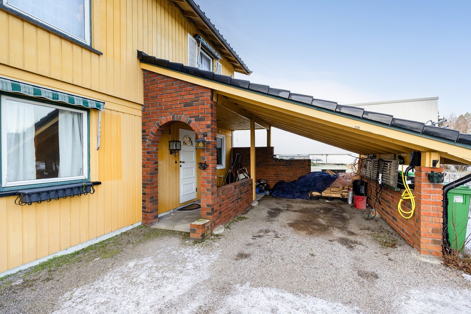 Carport tilliggende boligens inngangsparti gjør at man kan gå tørrskodd fra bilen og inn i boligen. Ladeboks til el-bil i carport etablert i 2022. Galleribilde