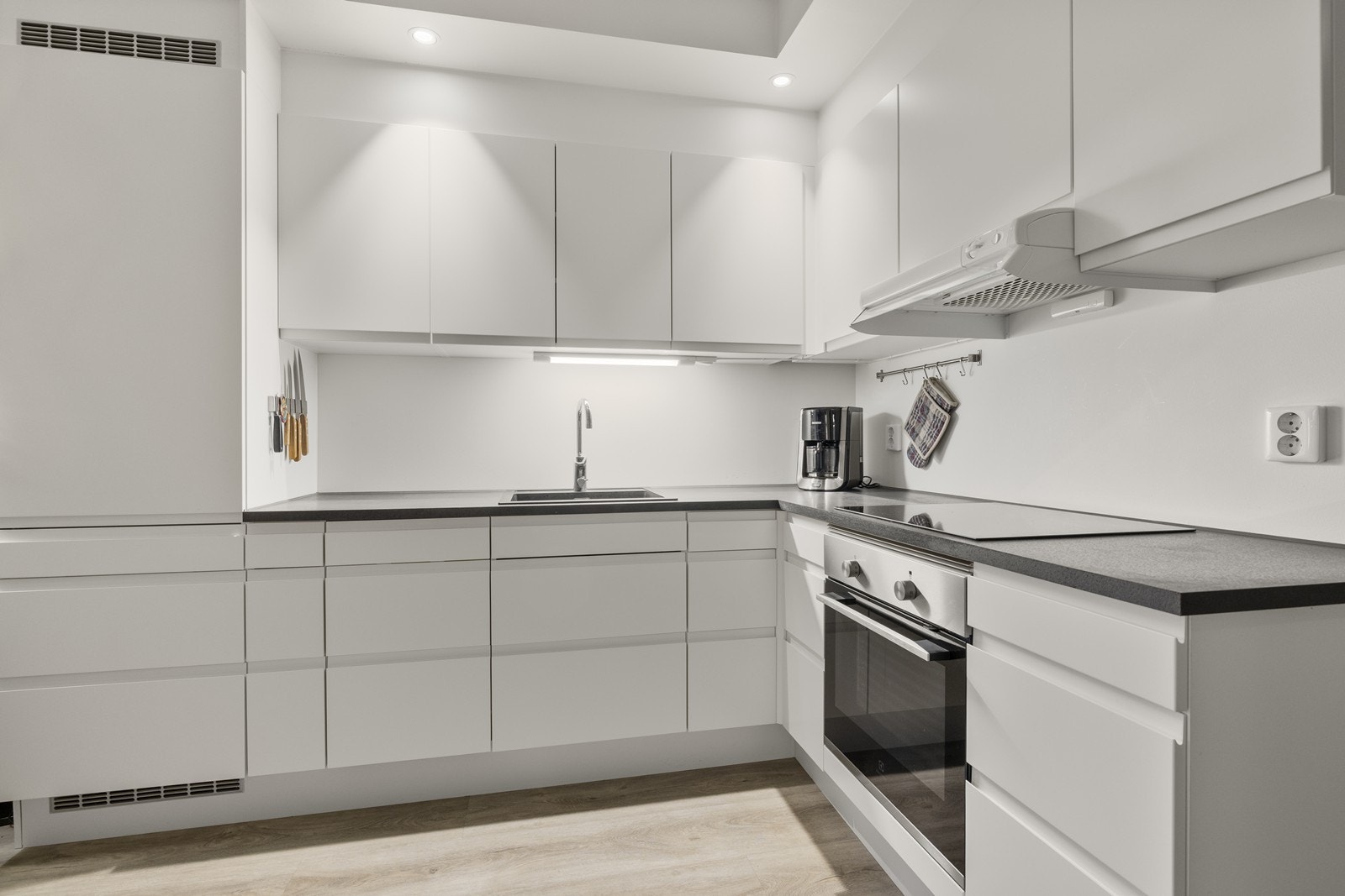 Kjøkkeninnredningen har slette, hvite fronter og en mørk laminatbenkeplate. Galleribilde