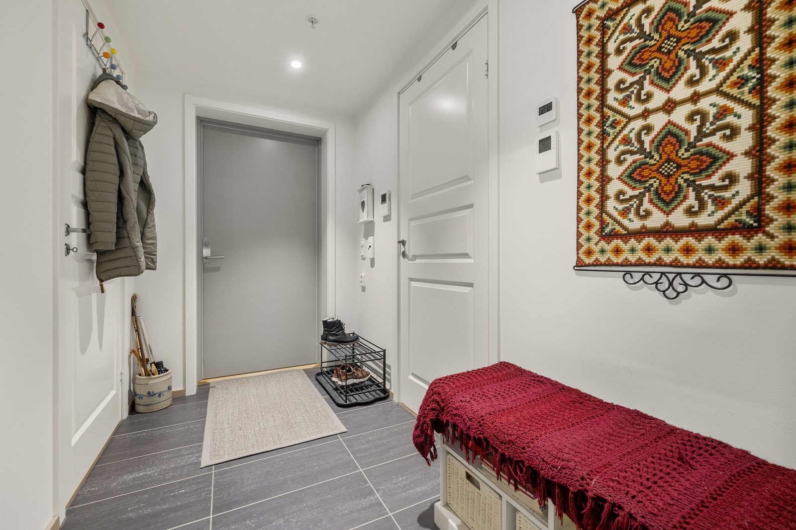 En innbydende entré med flislagt gulv og plass til oppbevaring av yttertøy. Galleribilde