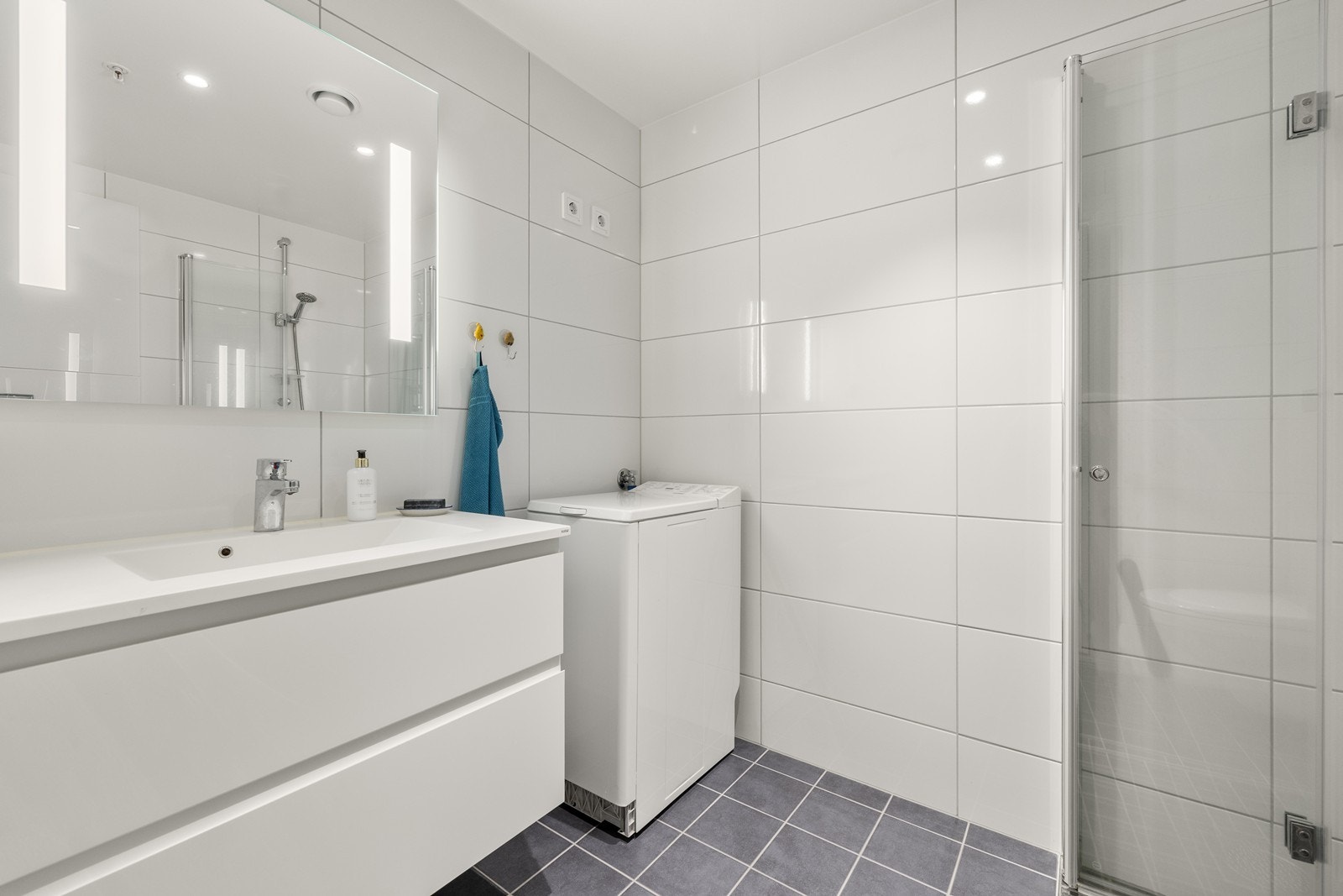 Badet er helfliset og utstyrt med servantmøbel, vegghengt toalett og opplegg for vaskemaskin. Galleribilde