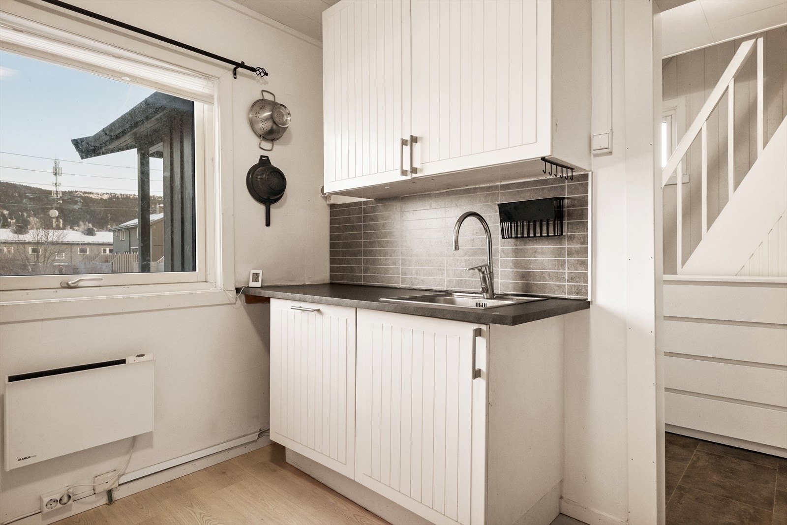 Kjøkken mot gang. Kjøkkeninnredning med laminerte skrog med
profilerte fronter. Laminerte benkeplater. Fliser og kjøkken-plater på vegger mellom benkeplater og overskap. Galleribilde