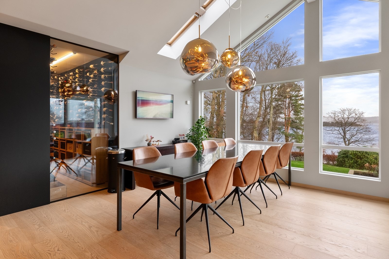 Lekker spisestue med panoramavinduer som gir fantastisk utsikt over vannet og omkringliggende natur samt innsyn til vinrommet. Perfekt for sammenkomster. Galleribilde