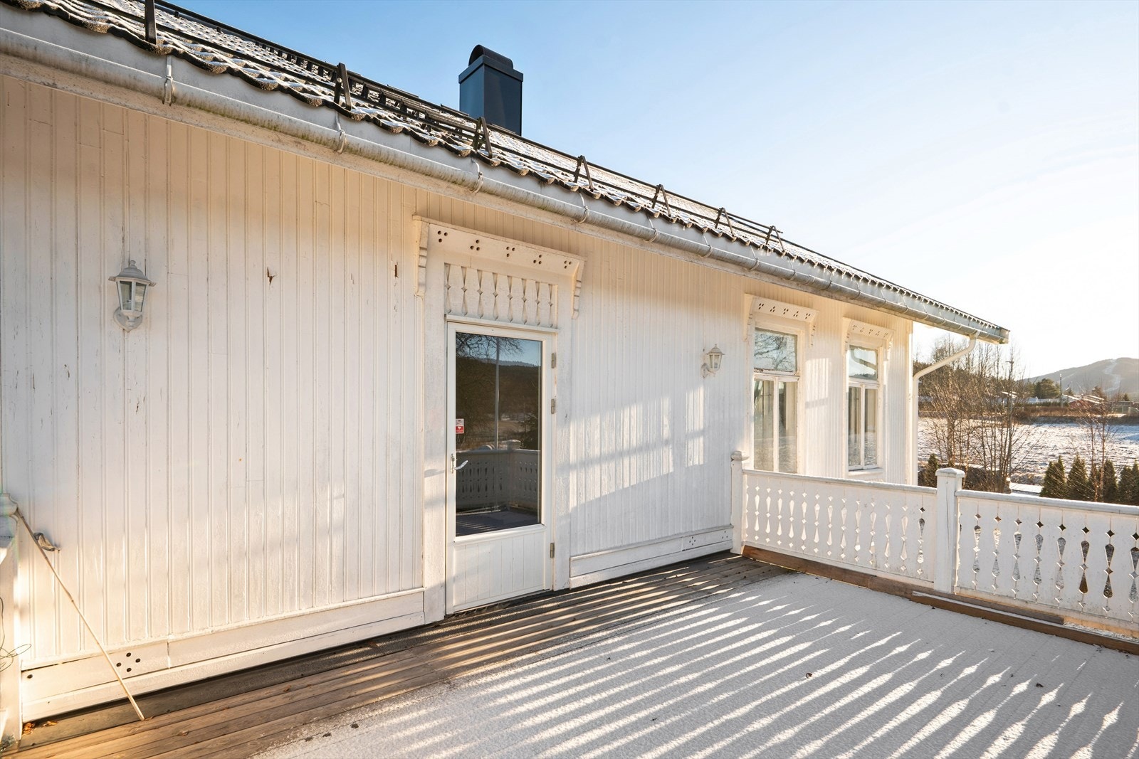 Terrassen har spaltegulv av impregnert treverk og et dekorativt rekkverk. Galleribilde