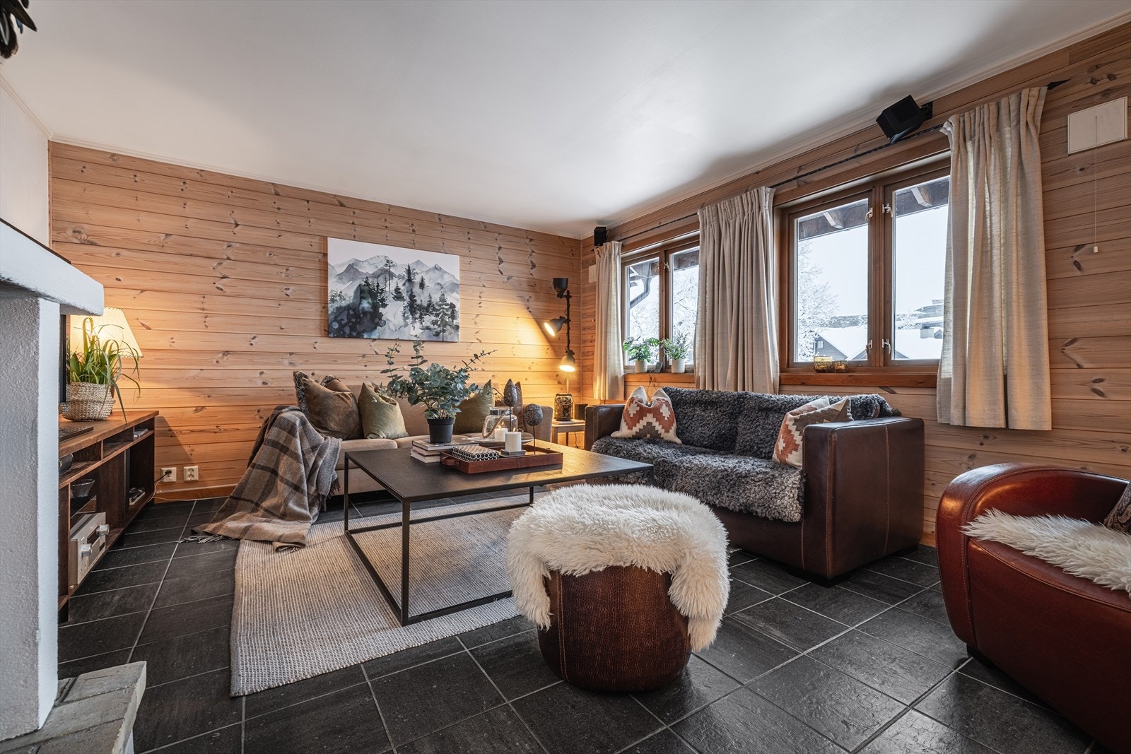 Stue med store vinduer som slipper inn naturlig lys og gir en varm og innbydende atmosfære. Galleribilde