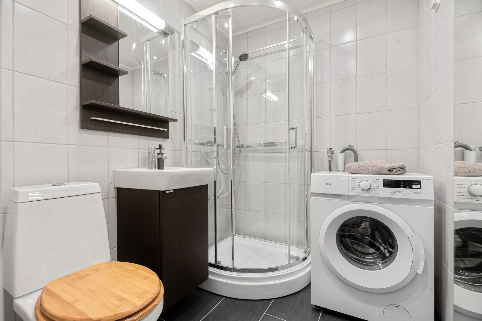 Badet er innredet med nedfelt servant, toalett, dusjkabinett og opplegg for vaskemaskin Galleribilde