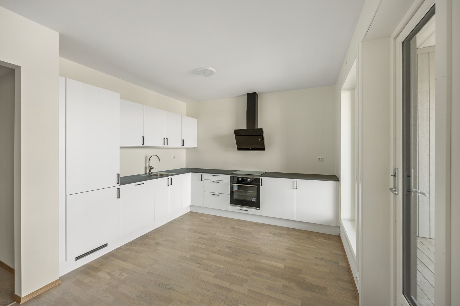 Lys og pen kjøkkeninnredning med integrert kjøl/fryseskap, stekeovn, platetopp og oppvaskmaskin Galleribilde