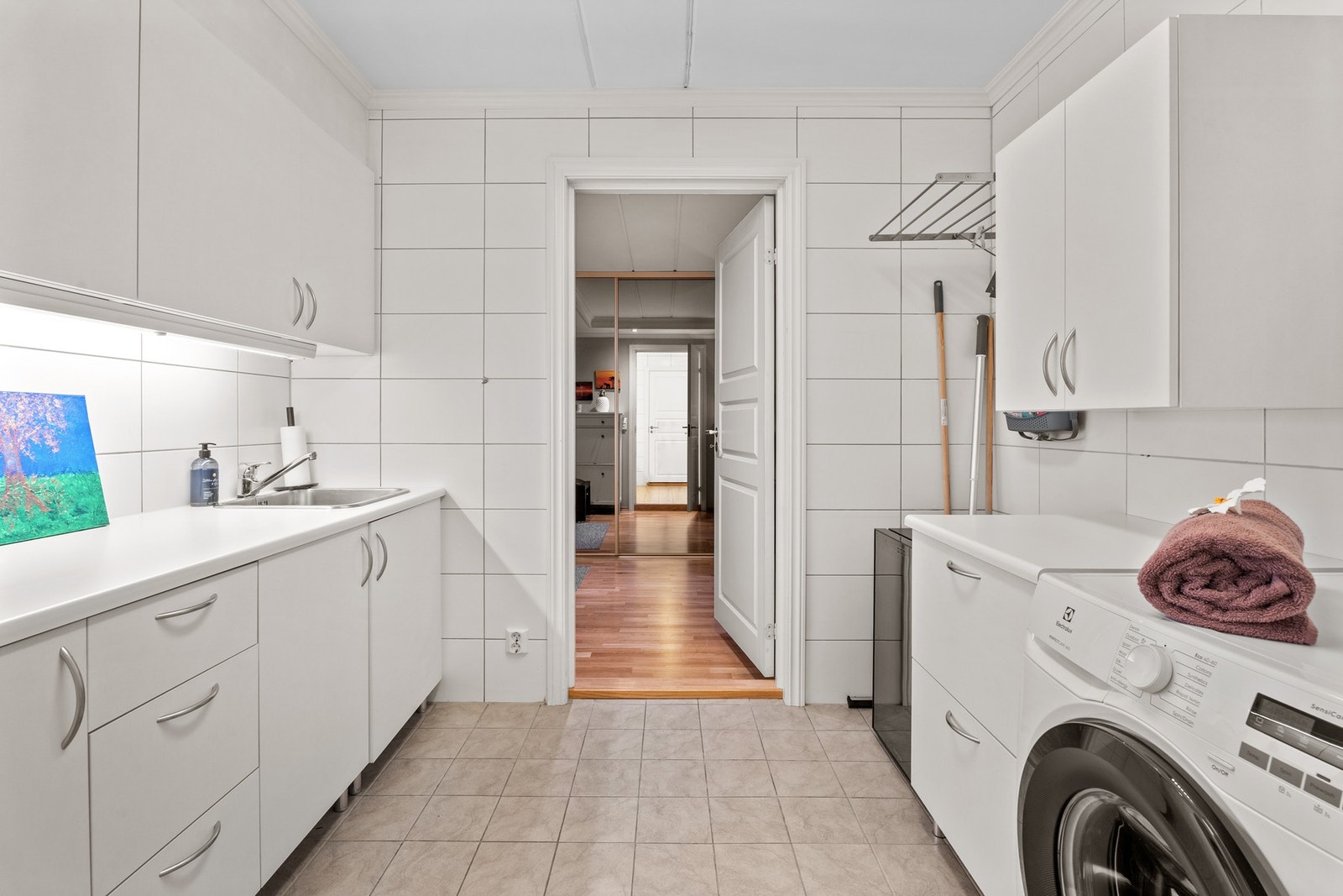 Praktisk og flislagt vaskerom med varmekabler, god benkeplass og opplegg for vaskemaskin. Galleribilde