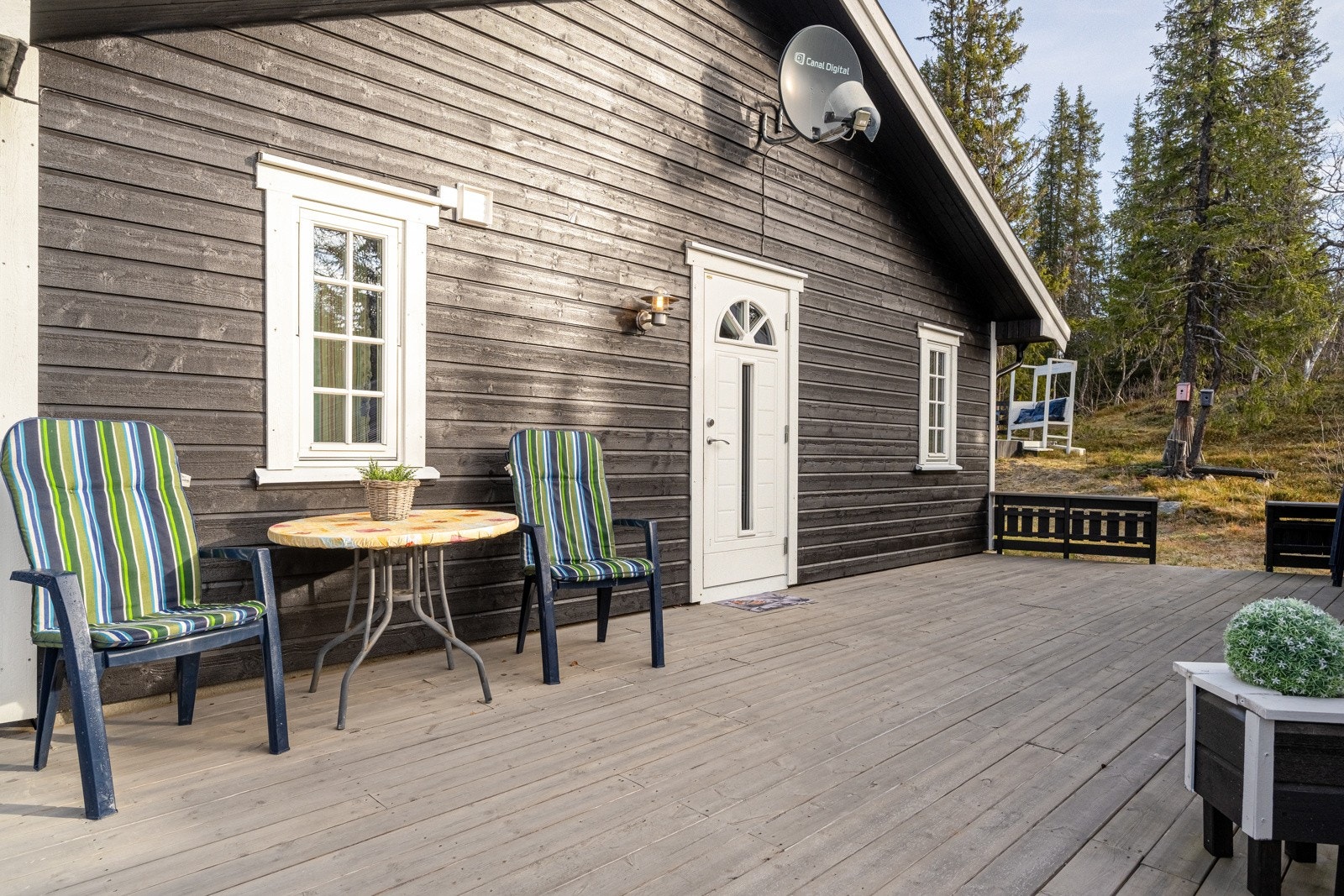 Inngangsparti med terrasse foran som omkranser to av hyttens vegger - perfekt sted for morgenkaffen Galleribilde