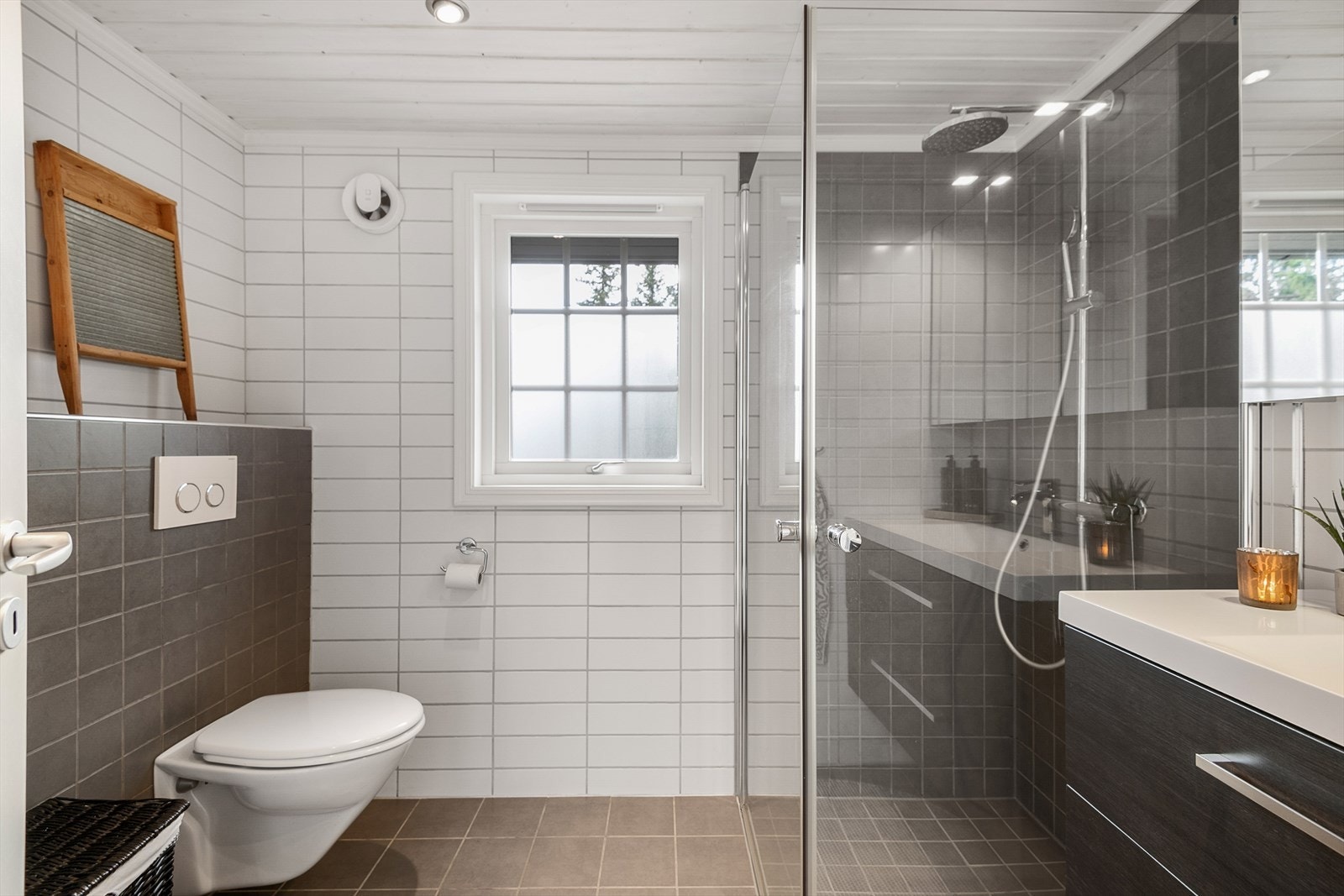 Stilrent og tidløst bad med dusjhjørne som har glassvegger, vegghengt WC og servantinnredning. Galleribilde