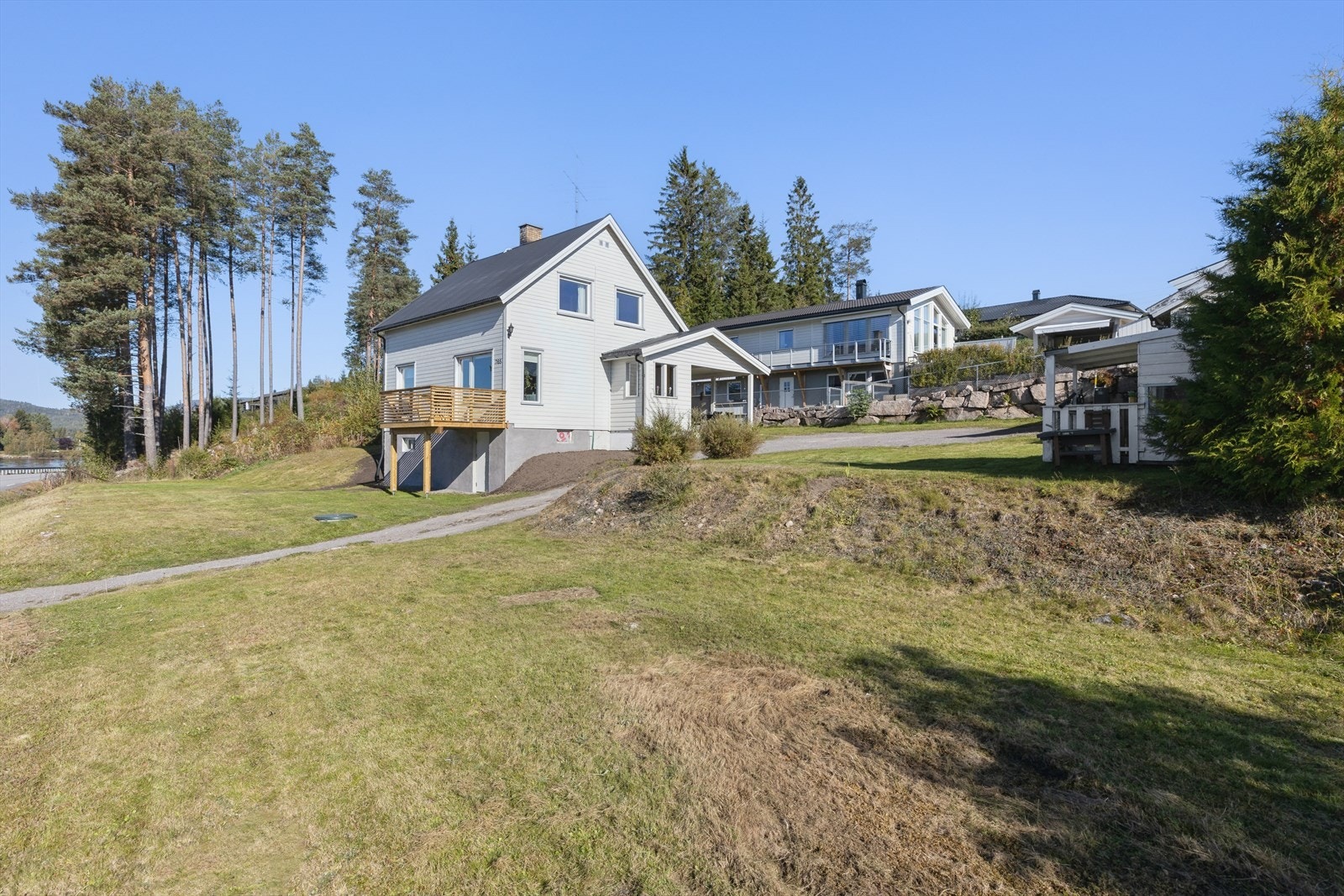 Tomten er flat/skrånende og opparbeidet med plen og noe beplantning Galleribilde