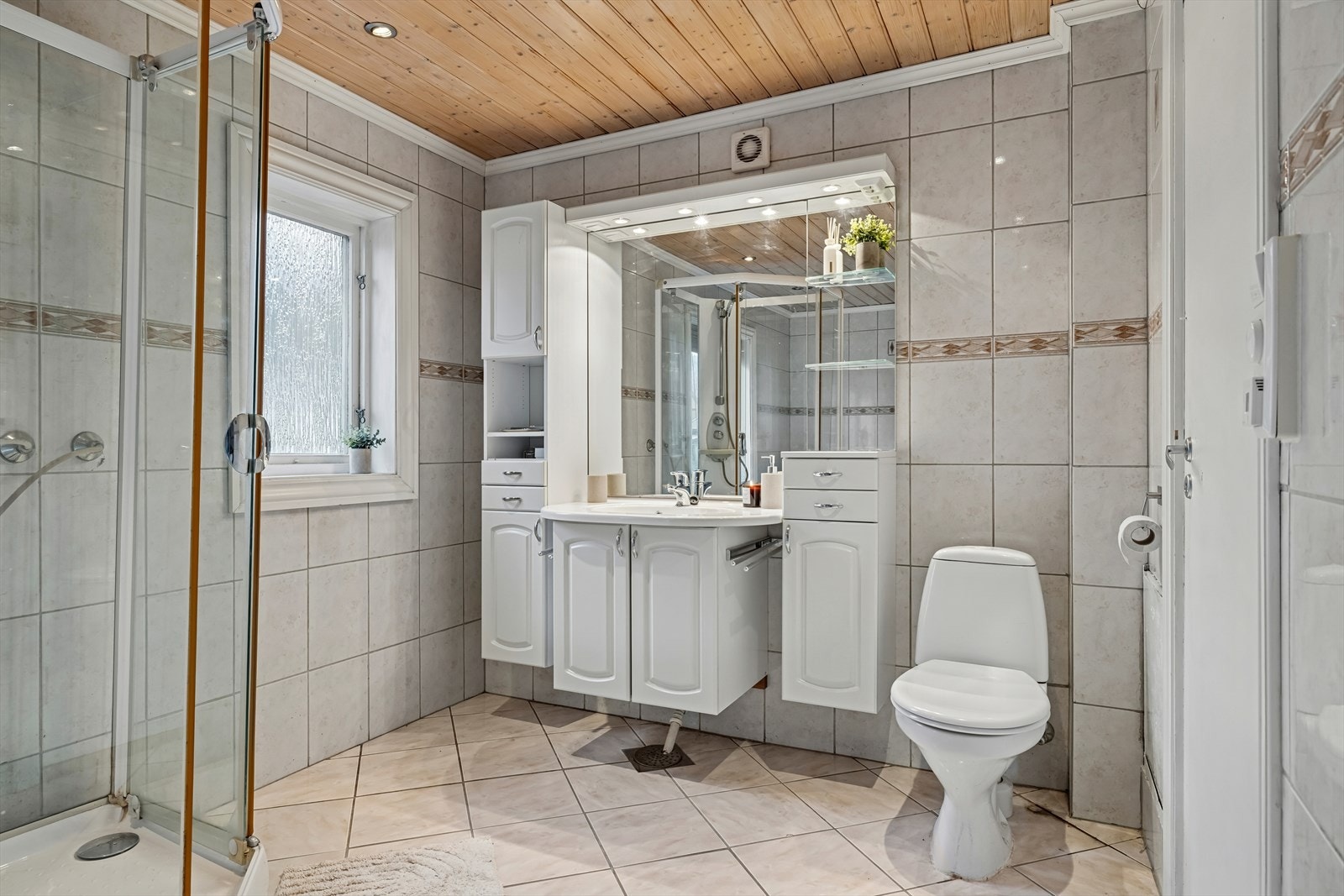 Badet er ellers utstyrt med hjørnebadekar, dusjkabinett, toalett og baderomsinnredning med nedfelt servant. Galleribilde