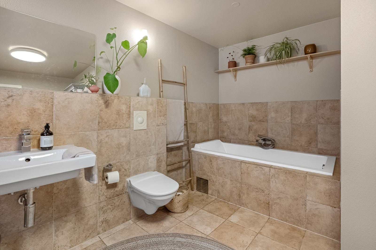 Fliselagt bad i hovedetasjen med vegghengt wc og badekar. Galleribilde