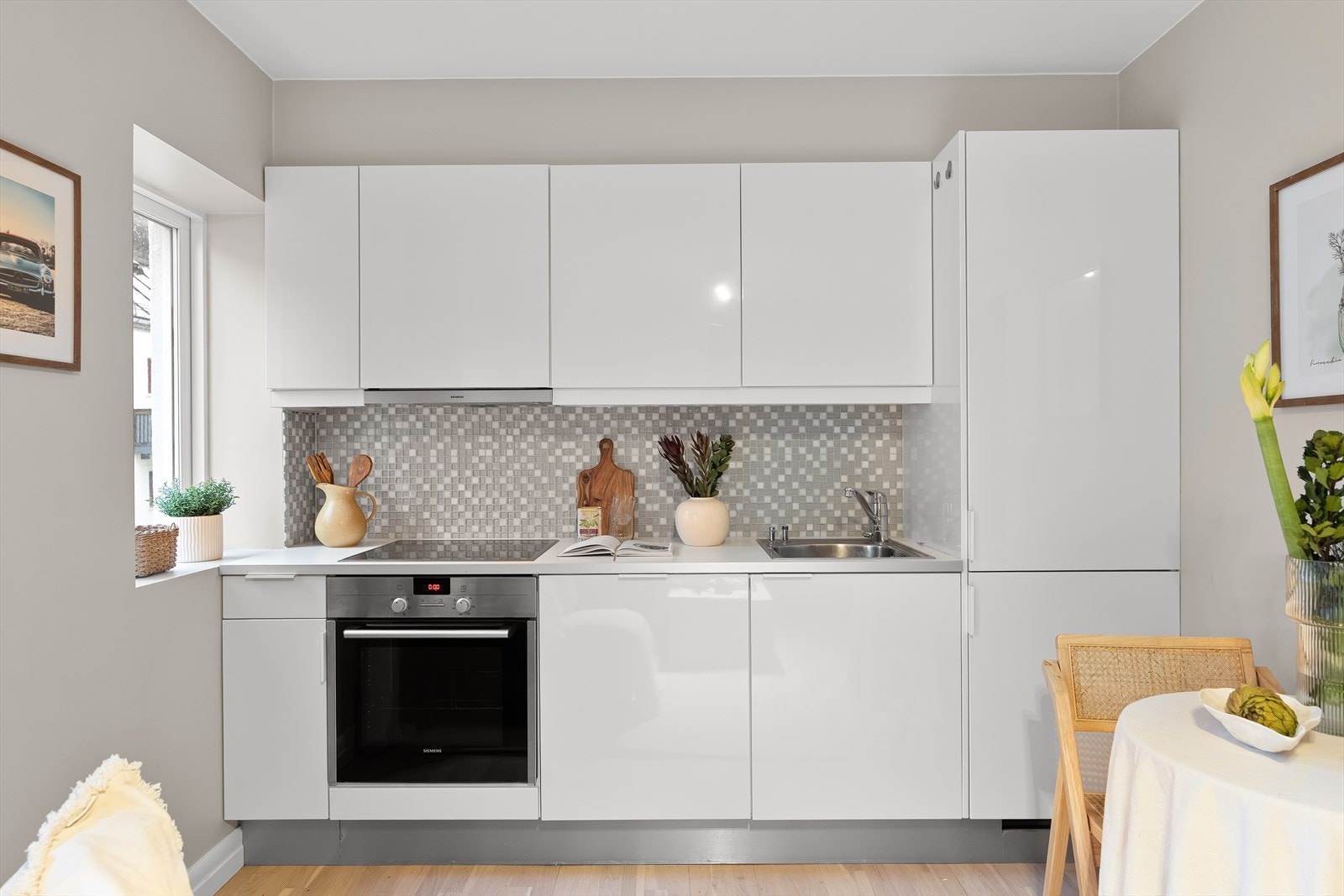 Pent kjøkken med innredning i glatte fronter og laminatbenkeplate. Nedfelt oppvaskkum i stål med ettgreps armatur fra Grohe. Galleribilde